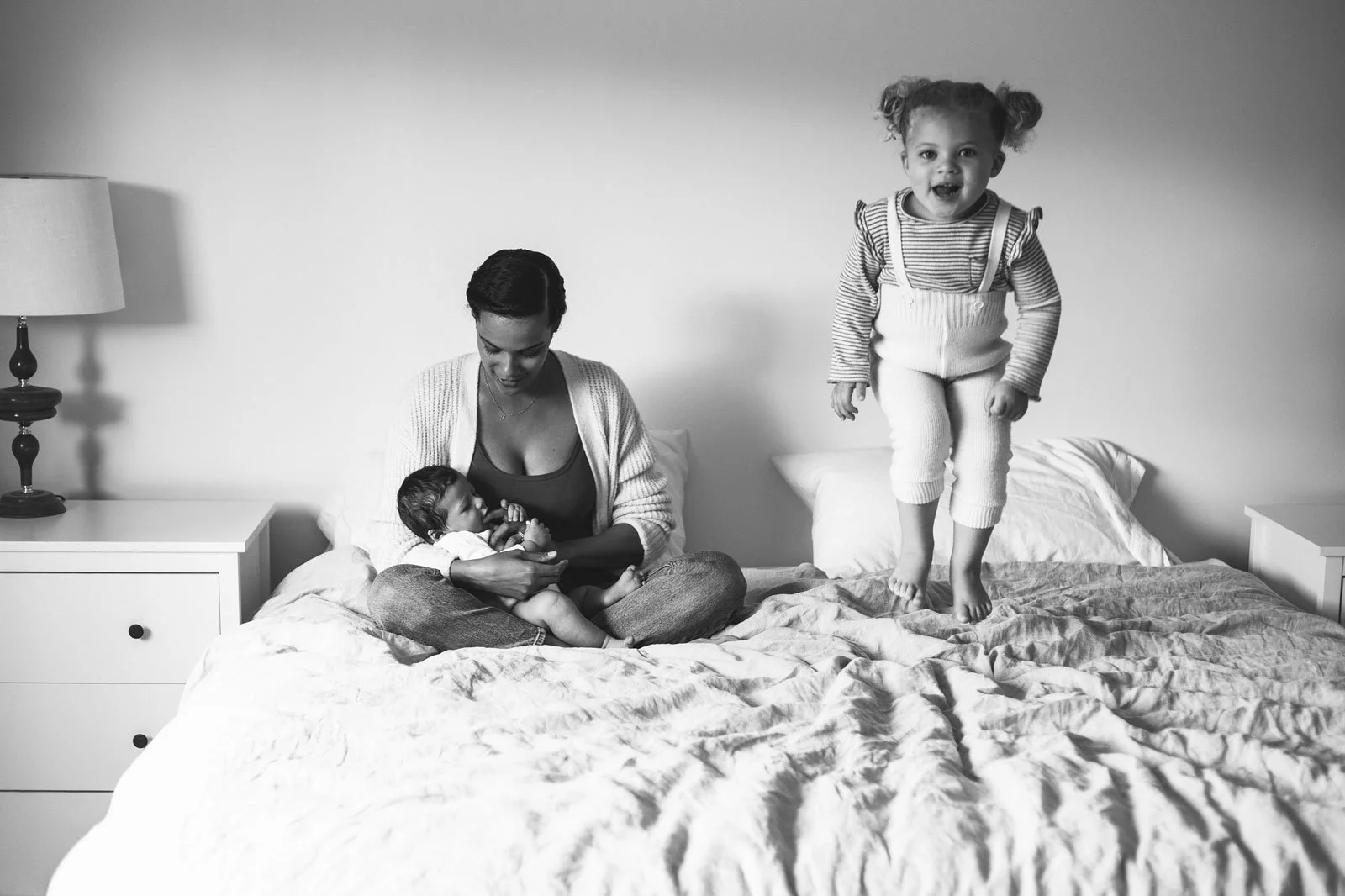 tri-cities-bc-family-photography-black-and-white-toddler-jumping-on-bed-candid.jpg