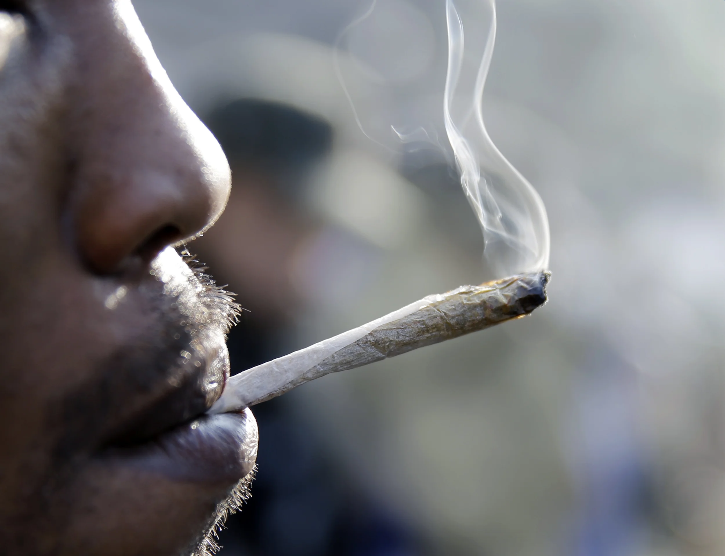 A man smokes a marijuana cigarette as a large group gathered near the New Jersey Statehouse to show their support for legalizing marijuana Saturday, March 21, 2015, in Trenton, N.J. (AP)