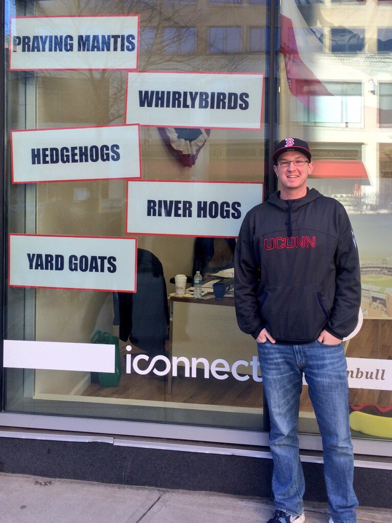 The author stands in front of the New Britain Rock Cats front office building during the team's re-branding process. The signs indicate new team names the franchise was considering. (Courtesy/Daniel Madigan)