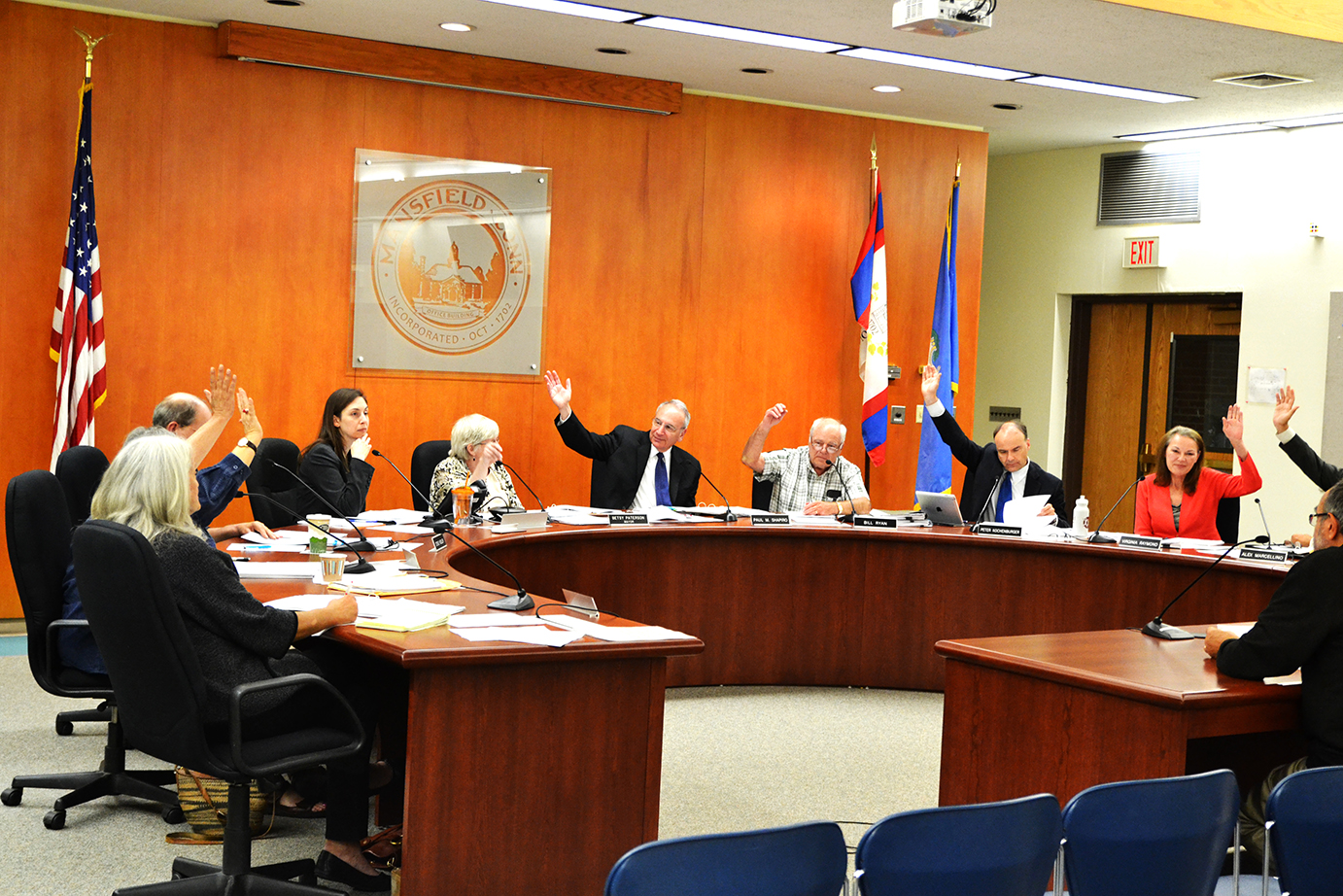 In this photo, members of the Mansfield Town Council raise their hands during a vote at a town council meeting in Mansfield, Connecticut on Monday, Sept. 28, 2015. (The Daily Campus)