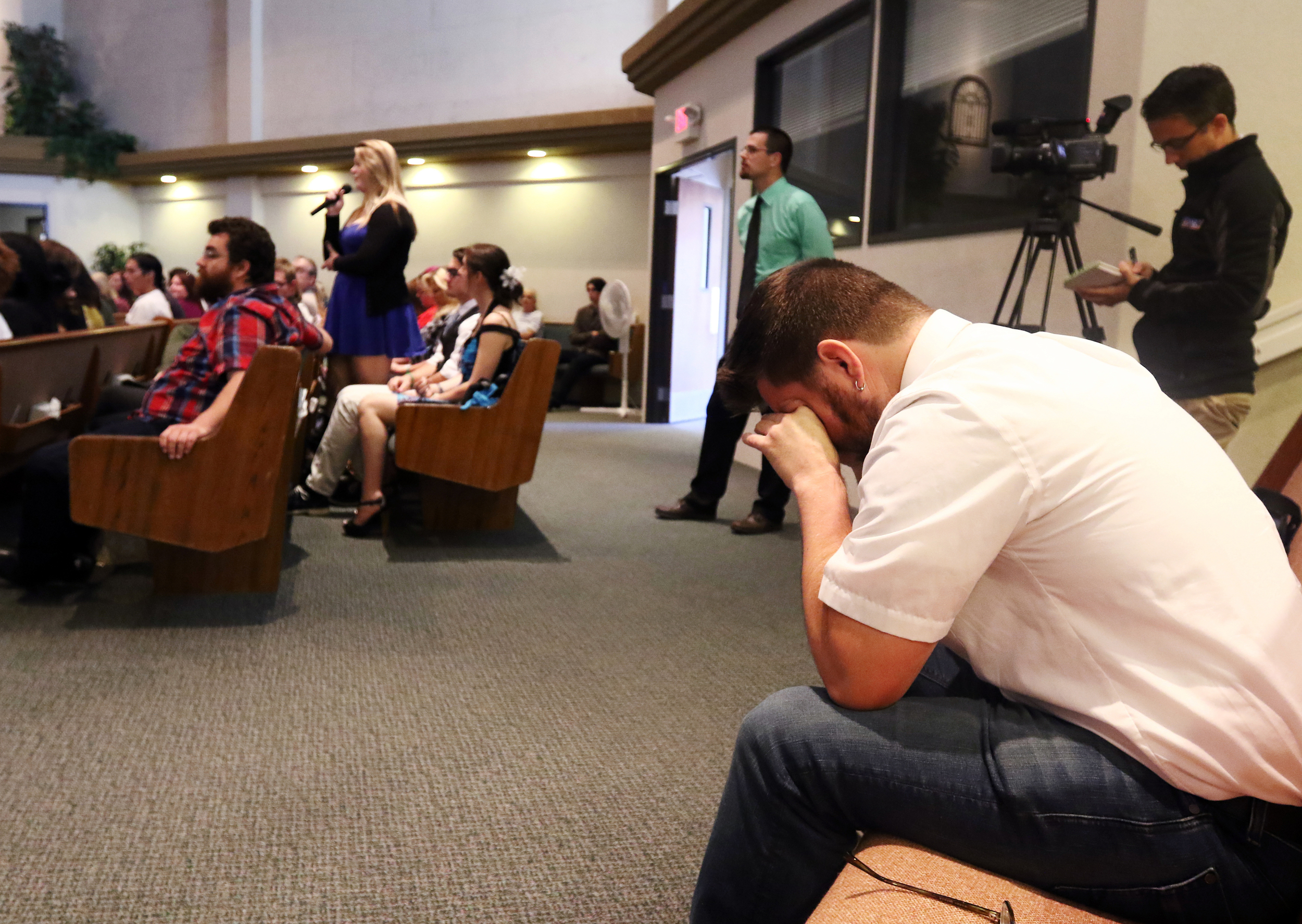 Former Roseburg High School math teacher Josh Carlton wipes away tears as Taylor Moore recounts a memory from her time as classmate of Quinn Cooper during a memorial for Cooper at Roseburg Christian Fellowship church in Roseburg, Ore., on Saturday, Oct. 10, 2015. Cooper was killed when a gunman opened fire at Umpqua Community College before turning the gun on himself after a shootout with police. (Michael Sullivan/The News-Review via AP)