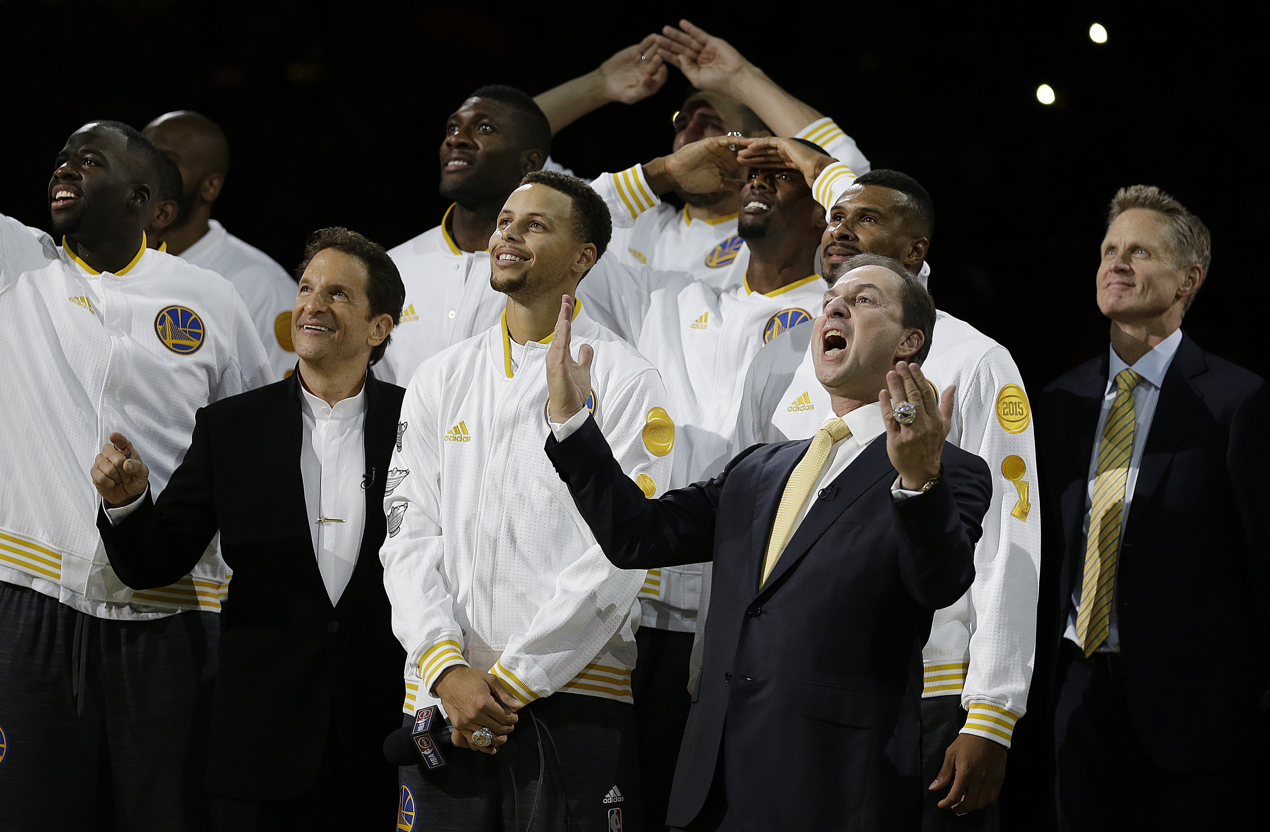 Golden State Warriors co-owner Joe Lacob, front right, reacts beside Stephen Curry and co-owner Peter Guber, second from left, as the Warriors championship banner is revealed during an awards ceremony to recognize the Warriors' NBA championship prior to a basketball game against the New Orleans Pelicans, Tuesday, Oct. 27, 2015, in Oakland, Calif. At right is Warriors coach Steve Kerr. (Ben Margot/AP)