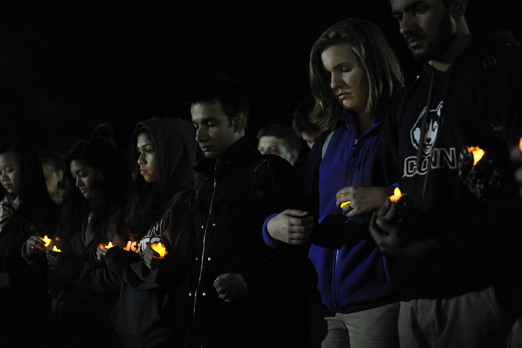 Students hold candles at the vigil on Fairfield Way. (Jason Jiang/Daily Campus)