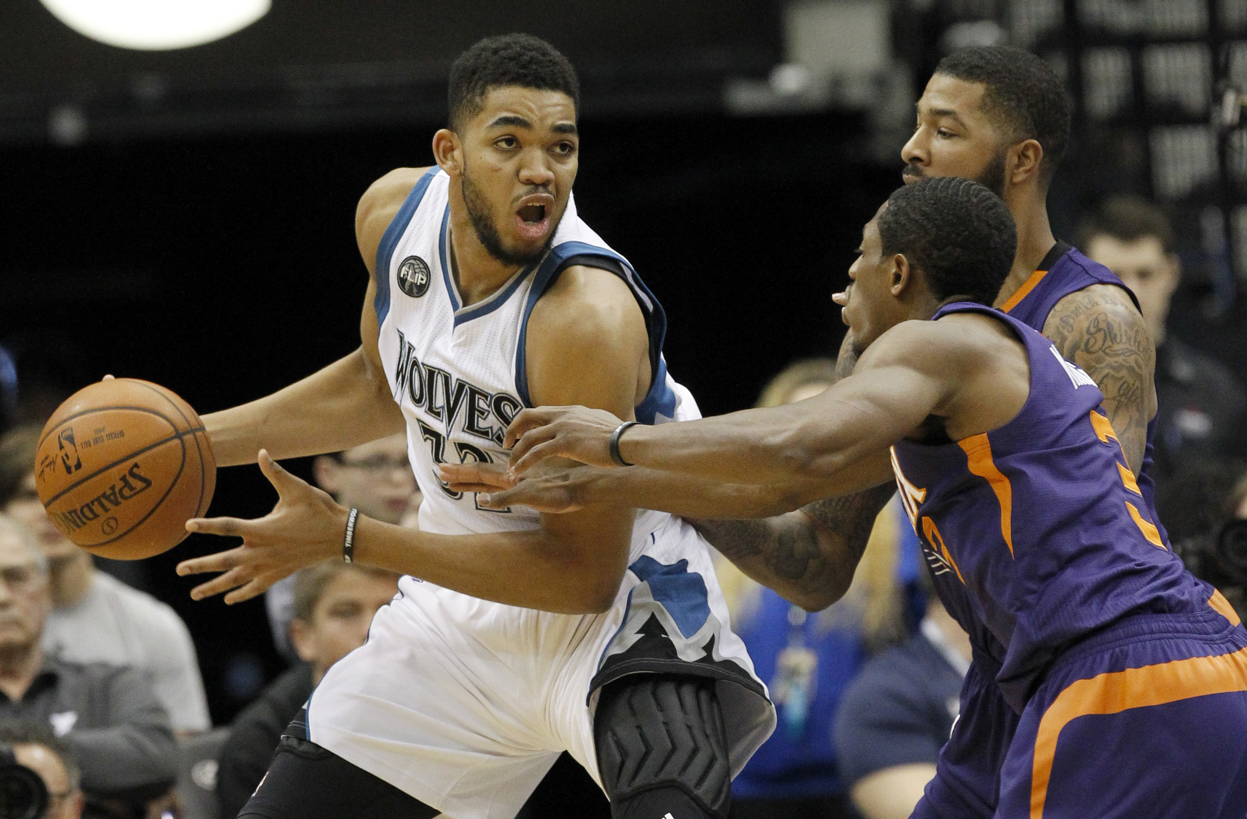 Minnesota Timberwolves center Karl-Anthony Towns, left, looks to pass to a teammate under pressure from Phoenix Suns forward Markieff Morris, right rear, and Suns guard Brandon Knight, right front, during the second half of an NBA basketball game in Minneapolis, Sunday, Jan. 17, 2016. (Ann Heisenfelt/AP)