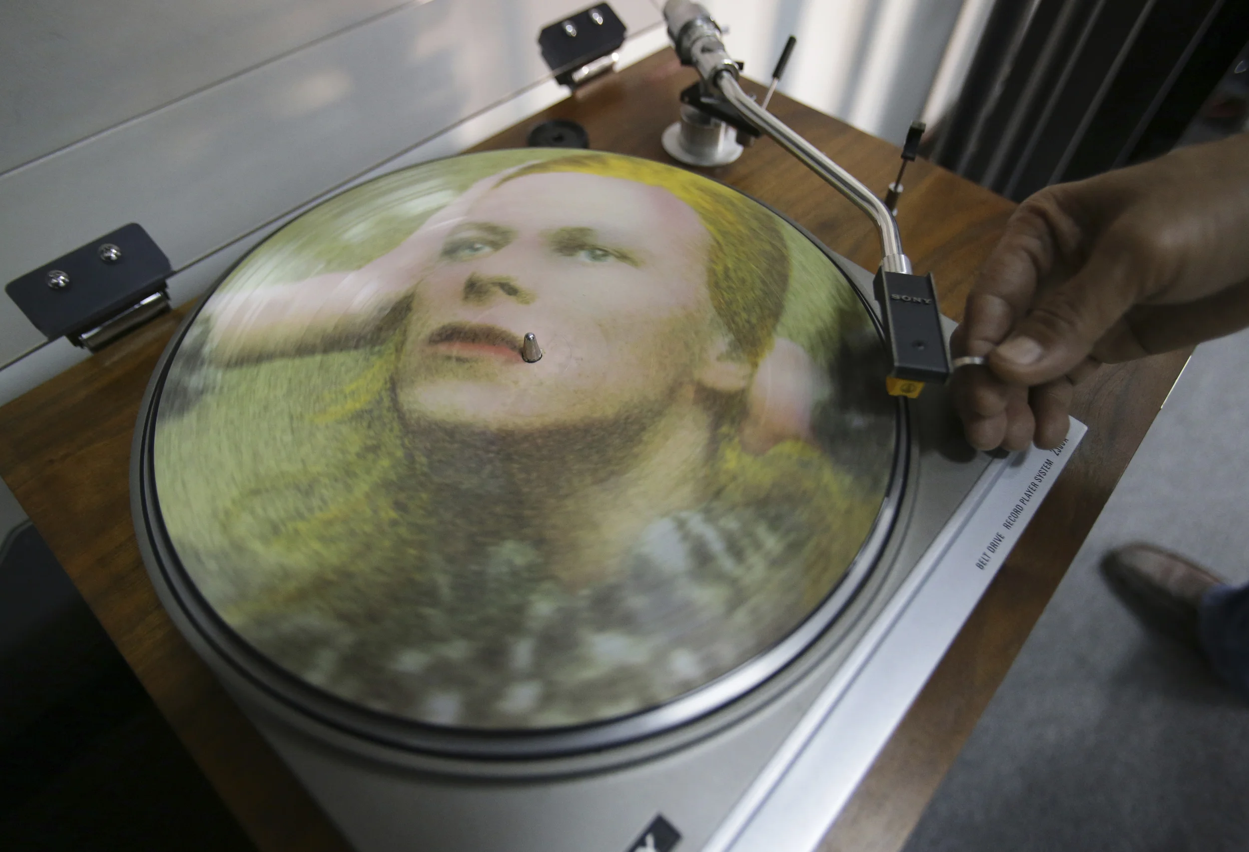 In this Tuesday, Jan. 12, 2016 photo, Rene Rivo, a Filipino David Bowie fan, plays a picture disc of Bowie's Hunky Dory on a turntable at his shop in suburban Paranaque, south of Manila, Philippines. (Aaron Favila, File/AP)