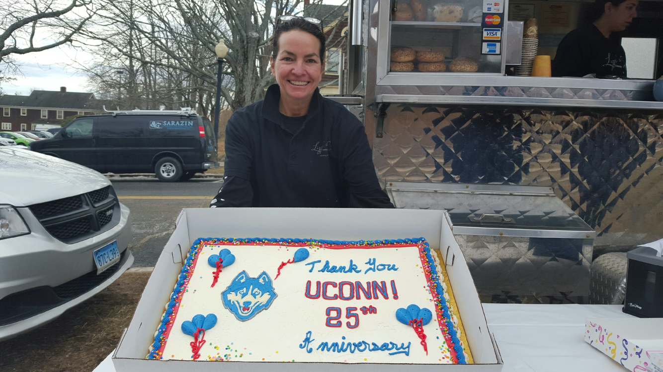 Lizzie Searing of Lizzie's Catering and Lizzie's Curbside, the well-known food truck often parked outside of the Arjona Building, holding her "thank you" cake marking her 25 years on campus. Cake and coffee was free this morning as part of the celebration. (Annabelle Orlando/Daily Campus)