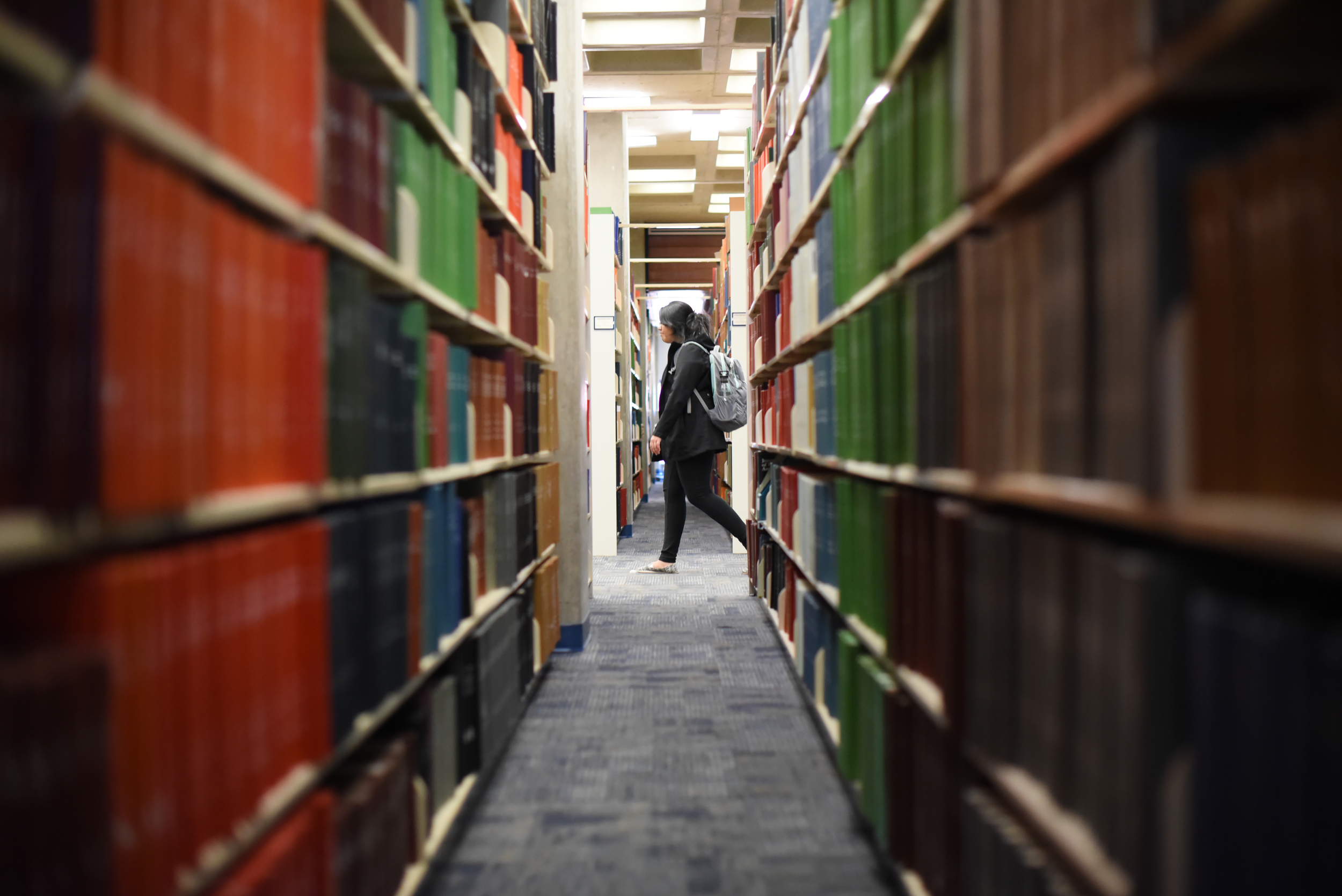 A student walks between rows of books in Homer Babbidge Library. Some students find it difficult to find time to read for fun during the semester, but others find the time to read books they love. (Zhelun Lang/Daily Campus)