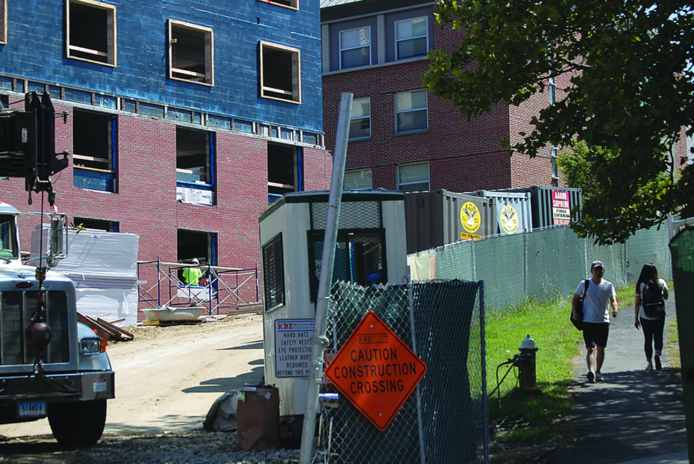 UConn students walk past construction last fall on the now-completed STEM residence hall, called the Next Generation Connecticut Halls, near the Putnam Refectory on Sept. 1, 2015. (Erika Elechicon/The Daily Campus)