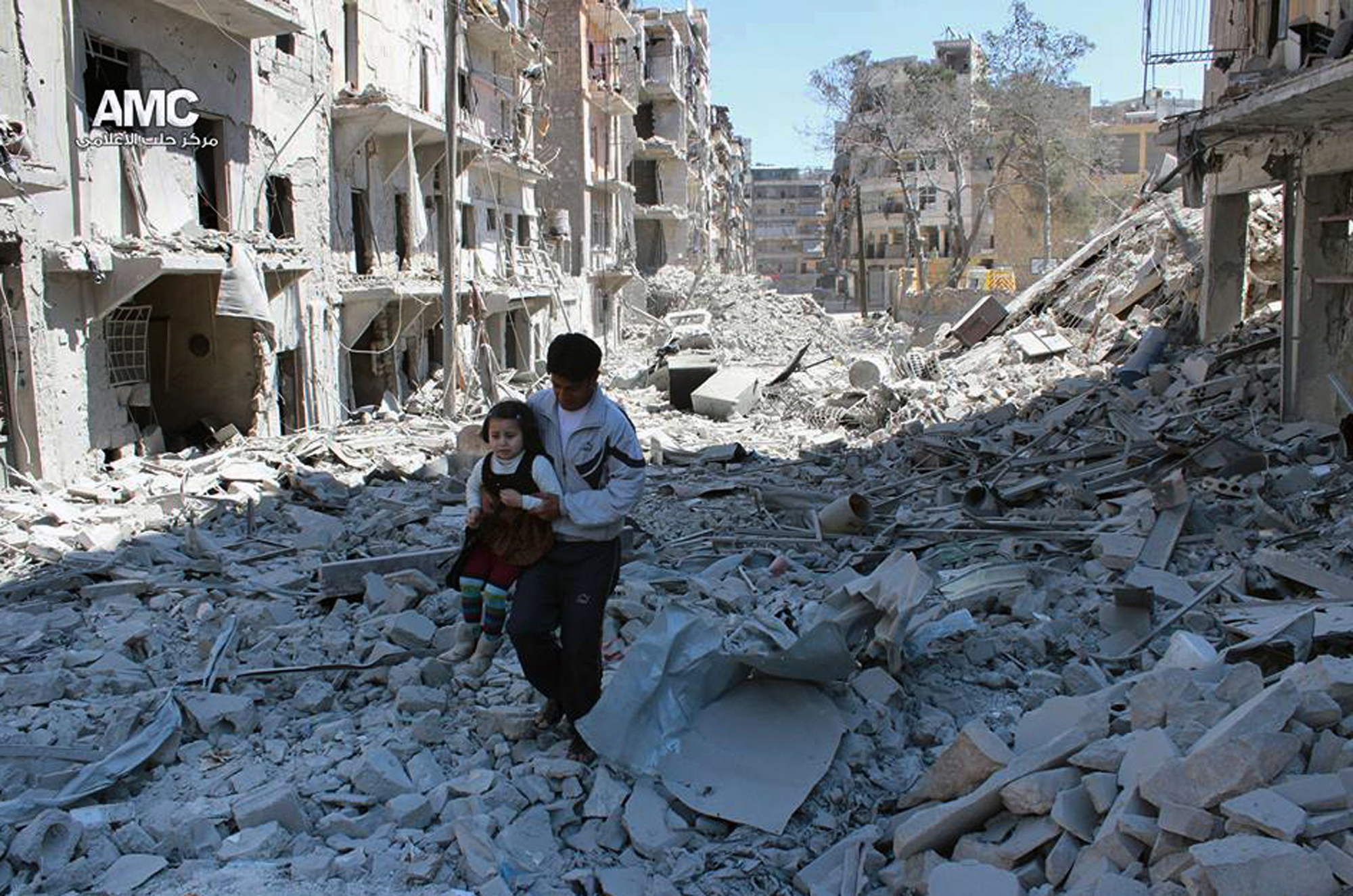 In This April 21, 2014, file photo, provided by the anti-government activist group Aleppo Media Center (AMC), which has been authenticated based on its contents and other AP reporting, shows a Syrian man holding a girl as he stands on the rubble of houses that were destroyed by Syrian government forces air strikes in Aleppo, Syria. (AP Photo/Aleppo Media Center AMC, File)