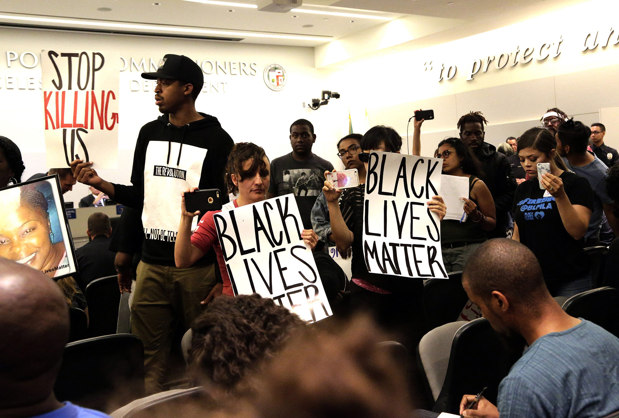 Black Lives Matter protesters demonstrate inside the board of Police Commissioners meeting in Los Angeles on Tuesday, Oct. 4, 2016. Los Angeles police released surveillance video Tuesday showing an 18-year-oldblack suspect running from police while holding what appears to be a gun in his left hand just before he was fatally shot by officers in a death that has generated rowdy protests. (Nick Ut/AP)
