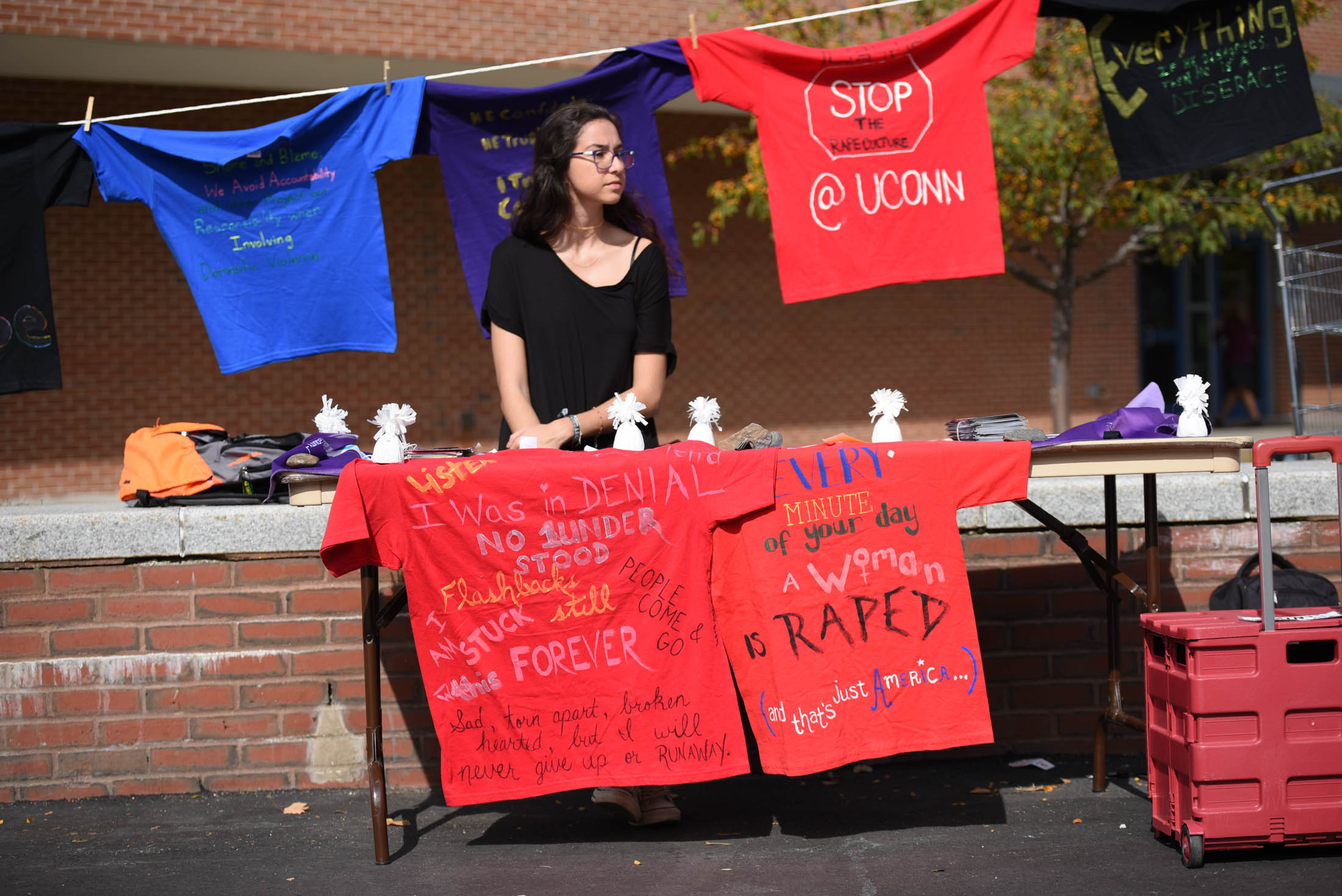 Manu Bayraktar, a junior geoscience major, volunteers for the annual Clothesline Project outside of the Student Union on Thursday, Oct. 13, 2016. Each t-shirt symbolizes the past and present experiences of a UConn student who has either suffered from sexual assault or been moved by survivors. (Zhelun Lang/The Daily Campus)