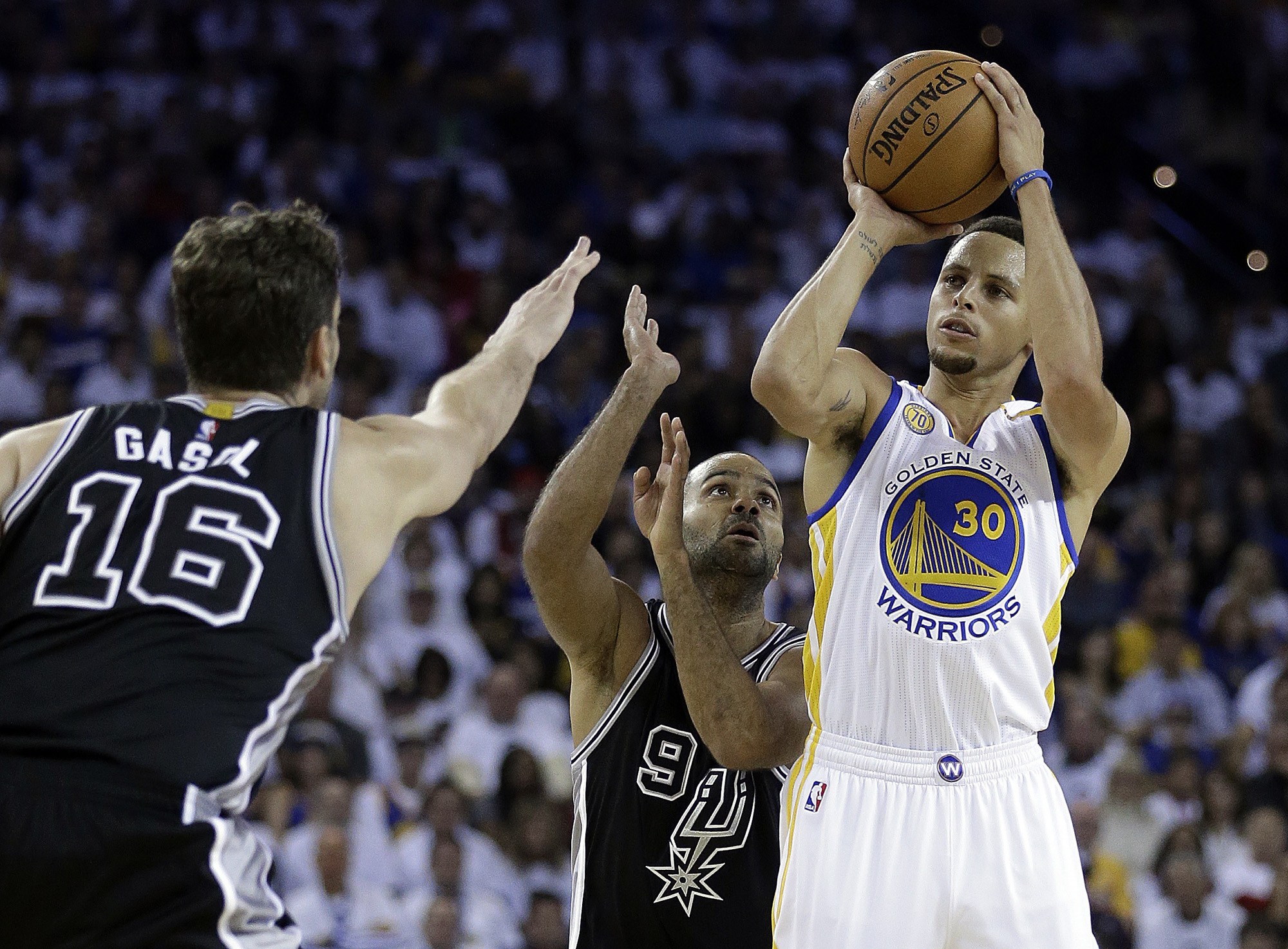 Golden State Warriors' Stephen Curry, right, shoots against San Antonio Spurs' Tony Parker (9) and Pau Gasol (16) during the first half of an NBA basketball game Tuesday, Oct. 25, 2016, in Oakland, Calif. (Ben Margot/ AP)