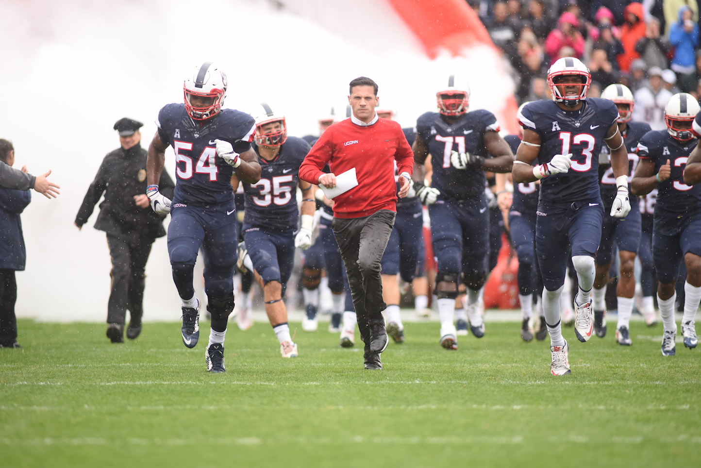 Head coach Bob Diaco runs out of the tunnel alongside senior linebacker Omaine Stephens (#54) and junior linebacker Vontae Diggs (#13) in a game against UCF on Oct. 23, 2016. The Huskies are looking to get back in the win column against ECU this weekend. (Zhelun Lang, The Daily Campus)