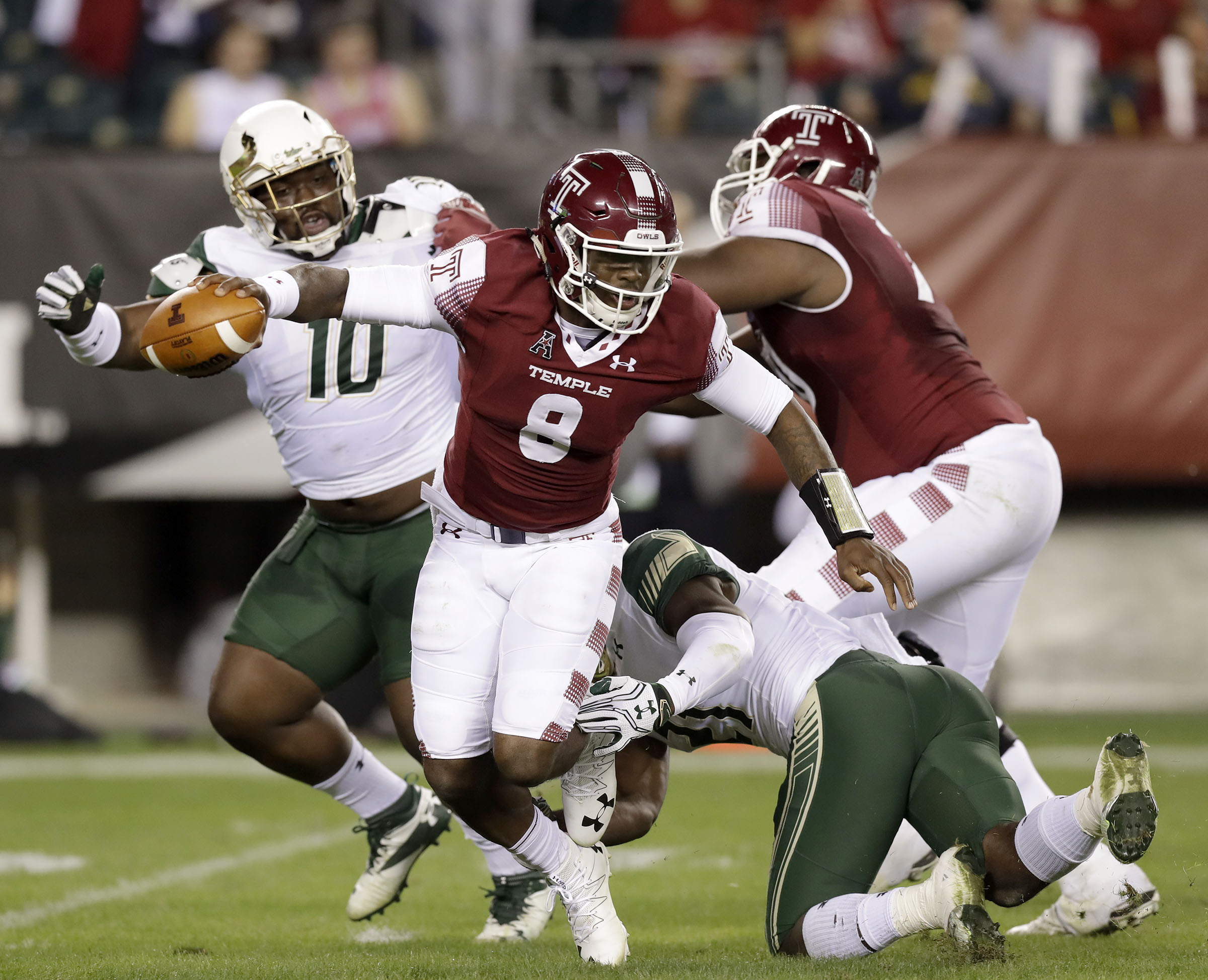 Temple quarterback Phillip Walker escapea from South Florida's Khalid McGee as Deadrin Senat, left, gets blocked by Temple offensive lineman Jovahn Fair during the first quarter of an NCAA college football game Friday, Oct. 21, 2016, in Philadelphia. (Yong Kim/The Philadelphia Inquirer via AP)