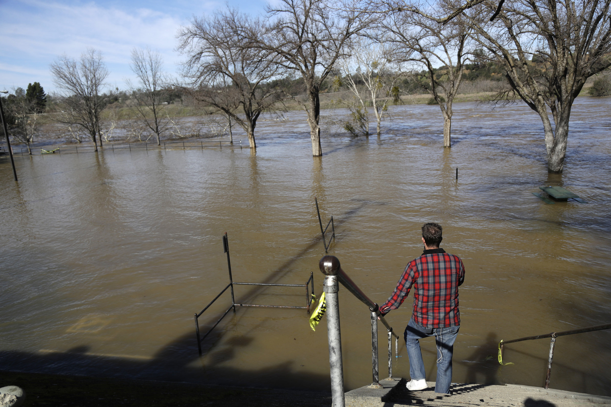 Rob McMillan, a television reporter from Los Angeles, reports from the overflowing Feather River Tuesday, Feb. 14, 2017, in Oroville, Calif. Workers are rushing to repair the barrier at the nation's tallest dam after authorities on Sunday ordered the evacuation for everyone living below the lake amid concerns the spillway could fail and send water roaring downstream. (Marcio Jose Sanchez/ AP)