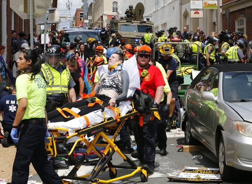 In this Aug. 12, 2017 file photo, rescue personnel help injured people who were hit when a car ran into a large group of protesters after a white nationalist rally in Charlottesville, Va. (AP Photo/Steve Helber, File)