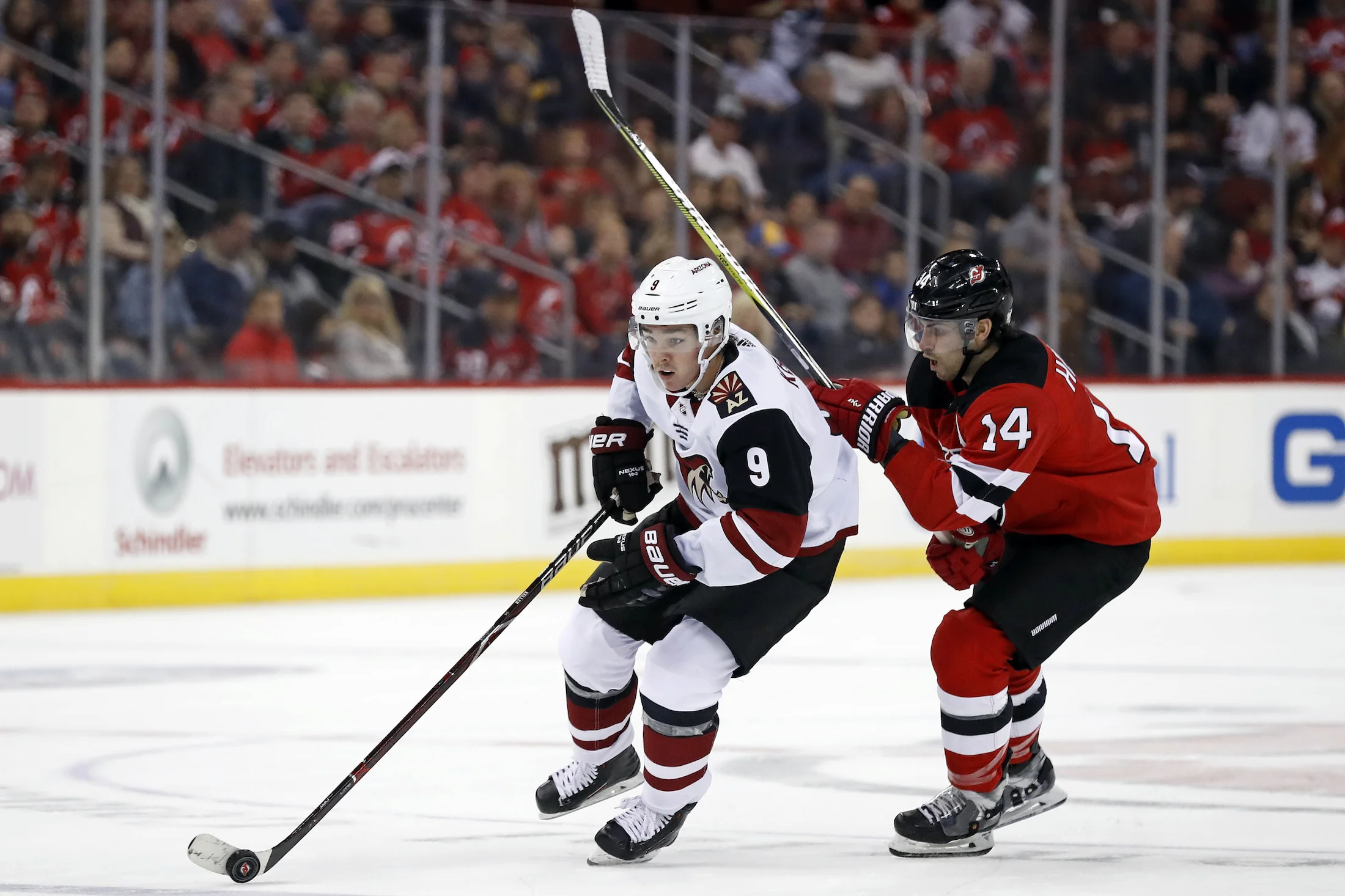 Arizona Coyotes' Clayton Keller (9) controls the puck past New Jersey Devils' Adam Henrique during the first period of an NHL hockey game, Saturday, Oct. 28, 2017, in Newark, N.J. (AP Photo/Adam Hunger)