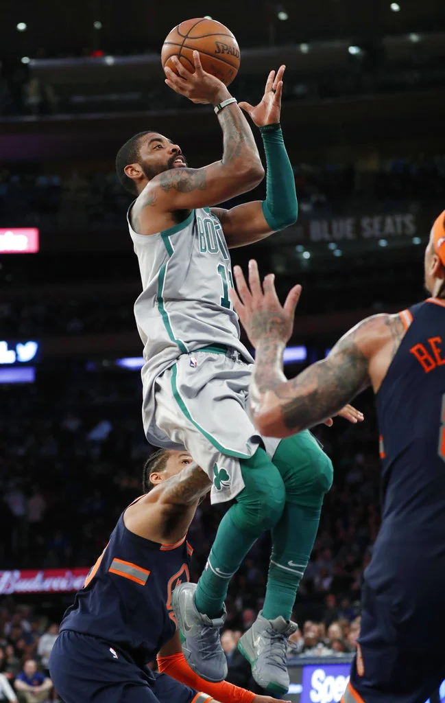 Boston Celtics guard Kyrie Irving, center, shoots over New York Knicks guard Trey Burke, during an NBA basketball game in New York, Saturday, Feb. 24, 2018. (AP Photo/Kathy Willens)