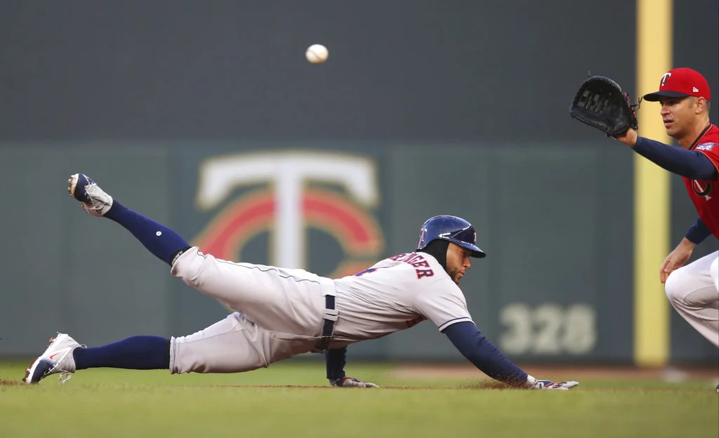 Houston Astros' George Springer dives safely back to first base as Minnesota Twins first baseman Joe Mauer waits for the throw during the first inning of a baseball game Tuesday, April 10, 2018, in Minneapolis. (AP Photo/Jim Mone)
