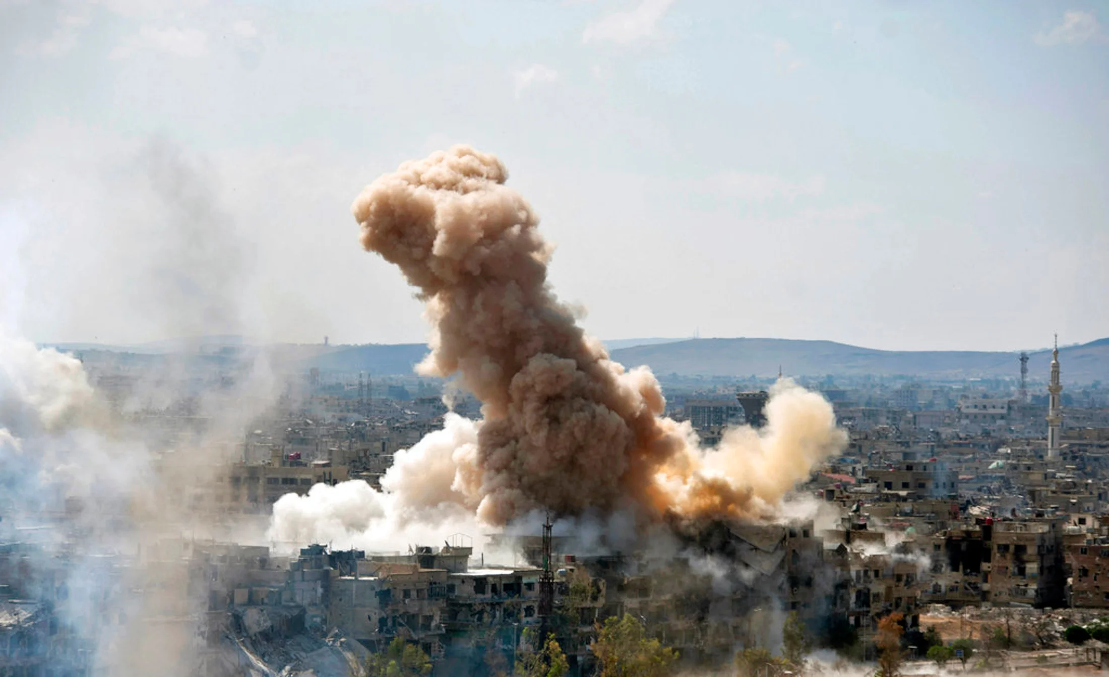 In this photo released by the Syrian official news agency SANA, smoke rises after Syrian government airstrikes and shelling hit in Hajar al-Aswad neighborhood held by Islamic State militants, southern Damascus, Syria, Sunday, April 22, 2018. Syrian state media says government forces are pounding districts of southern Damascus held by Islamic State militants with warplanes, helicopters and artillery in a bid to enforce an evacuation deal reached earlier in the week. (SANA via AP)