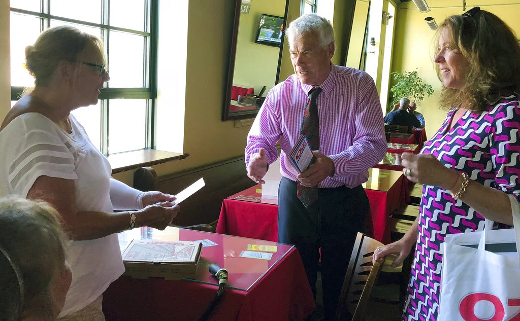In this July 18, 2018 photo, Oz Griebel, an independent candidate for governor in Connecticut, and his campaign finance director Kate Careb, right, greet voter Barbara "Bobbie" Seebeck of Groton while campaigning in New London, Conn. Seebeck said she has typically voted Republican, but likes the idea of supporting an independent this year. Independent candidate campaigns are working together, across state lines, to get their candidates elected in an era of hyper-partisanship. (AP Photo/Susan Haigh)