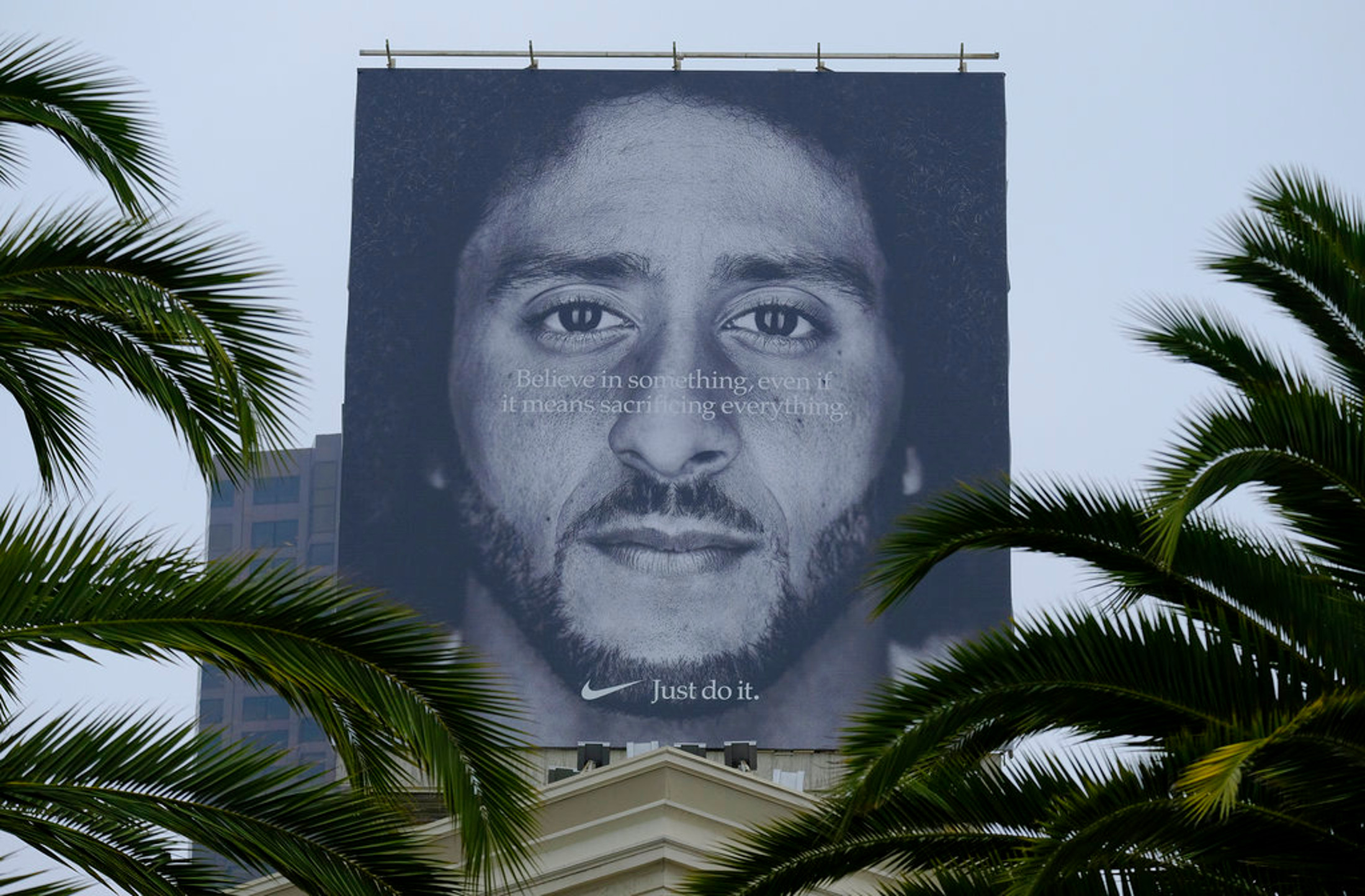 Palm trees frame a large billboard on top of a Nike store that shows former San Francisco 49ers quarterback Colin Kaepernick at Union Square, Wednesday, Sept. 5, 2018, in San Francisco. An endorsement deal between Nike and Colin Kaepernick prompted a flood of debate Tuesday as sports fans reacted to the apparel giant backing an athlete known mainly for starting a wave of protests among NFL players of police brutality, racial inequality and other social issues. (AP Photo/Eric Risberg)