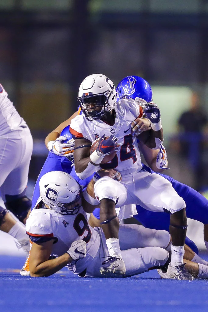 Connecticut running back Kevin Mensah center tries to spin away from Boise State defense in the second half of an NCAA college football game, Saturday, Sept. 8, 2018, in Boise, Idaho. Boise State won 62-7. (AP Photo/Steve Conner)