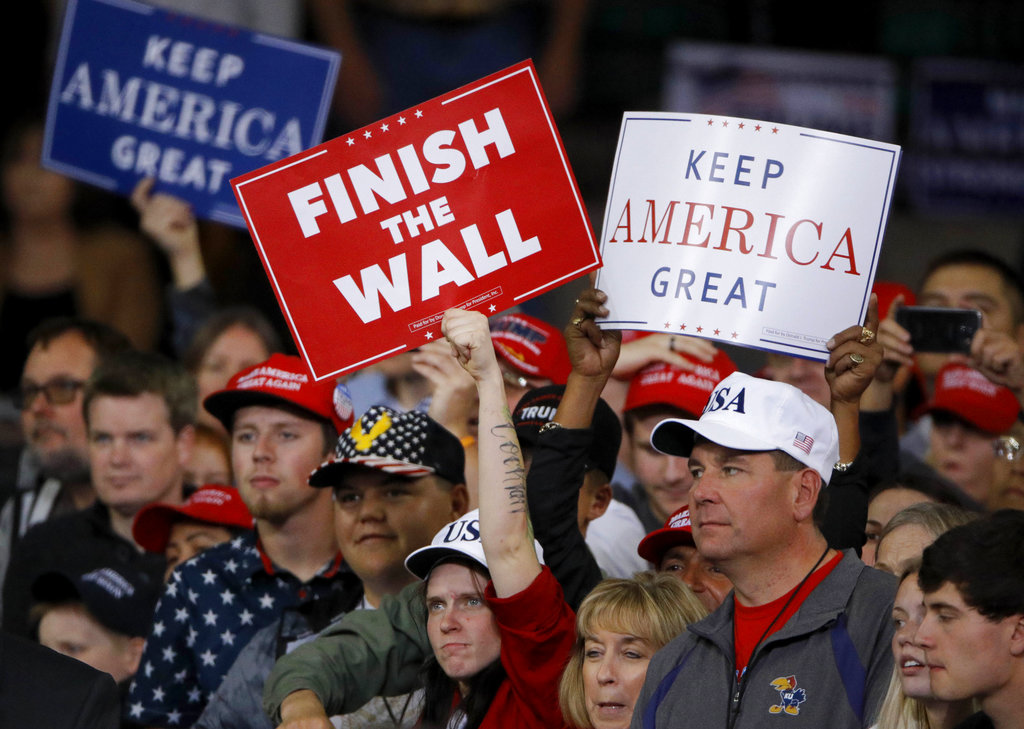 People watch as President Donald Trump addresses the crowd during a campaign rally Saturday, Oct. 6, 2018, in Topeka, Kan. (AP Photo/Charlie Riedel)