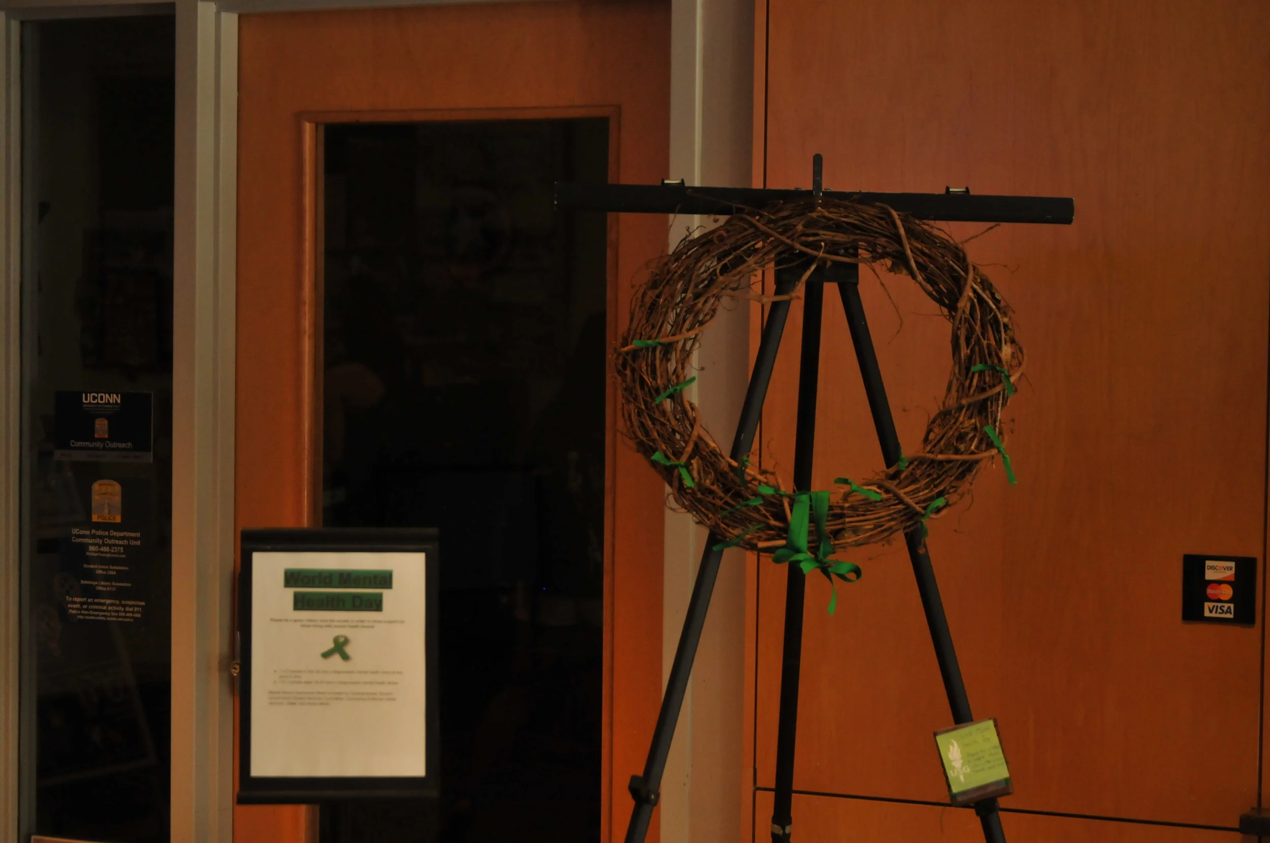 A wreath is placed in the Student Union to raise awareness for people struggling with mental health issues. People are encouraged to add a green ribbon by tying it to the wreath to show their support. (Brandon Barzola/The Daily Campus)