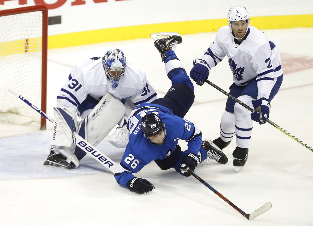 Winnipeg Jets' Blake Wheeler (26) crashes over Toronto Maple Leafs goaltender Frederik Andersen (31) after colliding with Ron Hainsey (2) during first period NHL hockey action in Winnipeg, Manitoba, Wednesday, Oct. 24, 2018. (Trevor Hagan/The Canadian Press via AP)