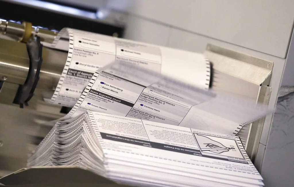 Ballots flip out of a machine scanning them at the King County Elections office Monday, Nov. 5, 2018, in Renton, Wash. The new machine can scan up to 17,000 ballots an hour, considerably more than machines previously used there that could, at best, scan 1,200 ballots in an hour. (AP Photo/Elaine Thompson)