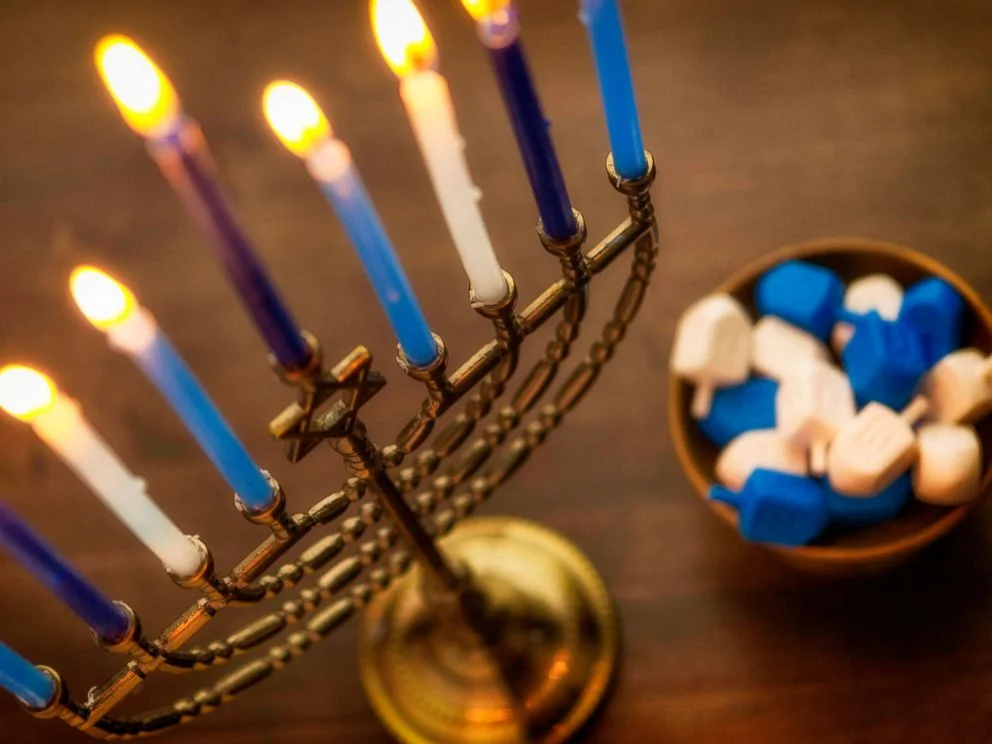 Menorah with burning candles and dreidel. What you need to know about Hanukkah By LINDSEY JACOBSON. Nov 27, 2018, 11:21 AM ET
