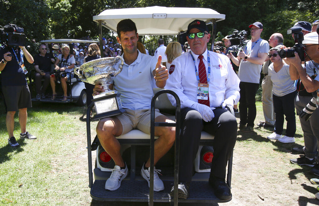 Serbia's Novak Djokovic gestures as he rides with his trophy, the Norman Brookes Challenge Cup, at Melbourne's Royal Botanic Gardens following his win over Rafael Nadal of Spain in the men's singles final at the Australian Open tennis championships in Melbourne, Australia, Monday, Jan. 28, 2019. (AP Photo/Aaron Favila)