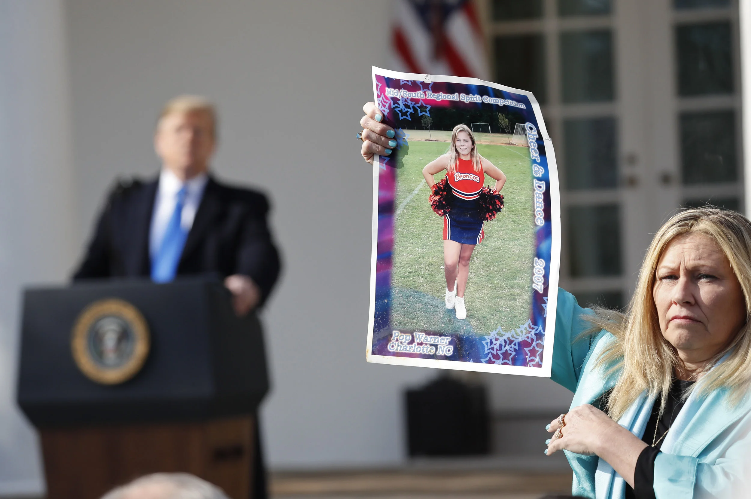 President Donald Trump, left, looks over to Susan Stevens, right, who is holding up a picture of her daughter, during an event in the Rose Garden at the White House to declare a national emergency in order to build a wall along the southern border, Friday, Feb. 15, 2019 in Washington. Stevens lost her daughter to opioids. (AP Photo/Pablo Martinez Monsivais)