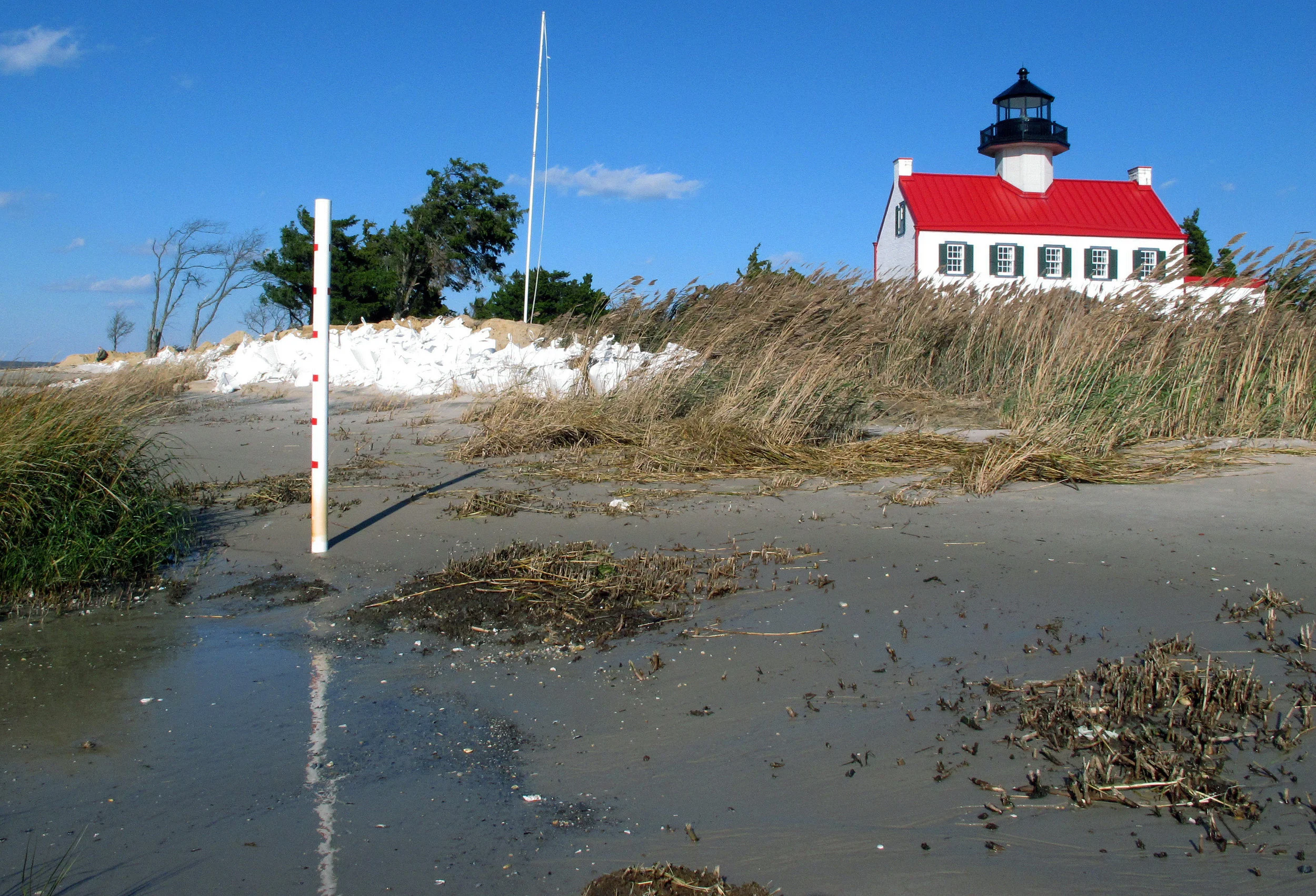 In this Nov. 10, 2018, file photo, water from the Delaware Bay approaches the East Point Lighthouse in Maurice River Township, N.J. Rising seas and erosion are threatening lighthouses around the world, including the East Point Lighthouse. As climate change becomes a hotter topic in American classrooms in 2019, some politicians are pushing back against the scientific consensus that global warming is real and man-made. (AP Photo/Wayne Parry, File)
