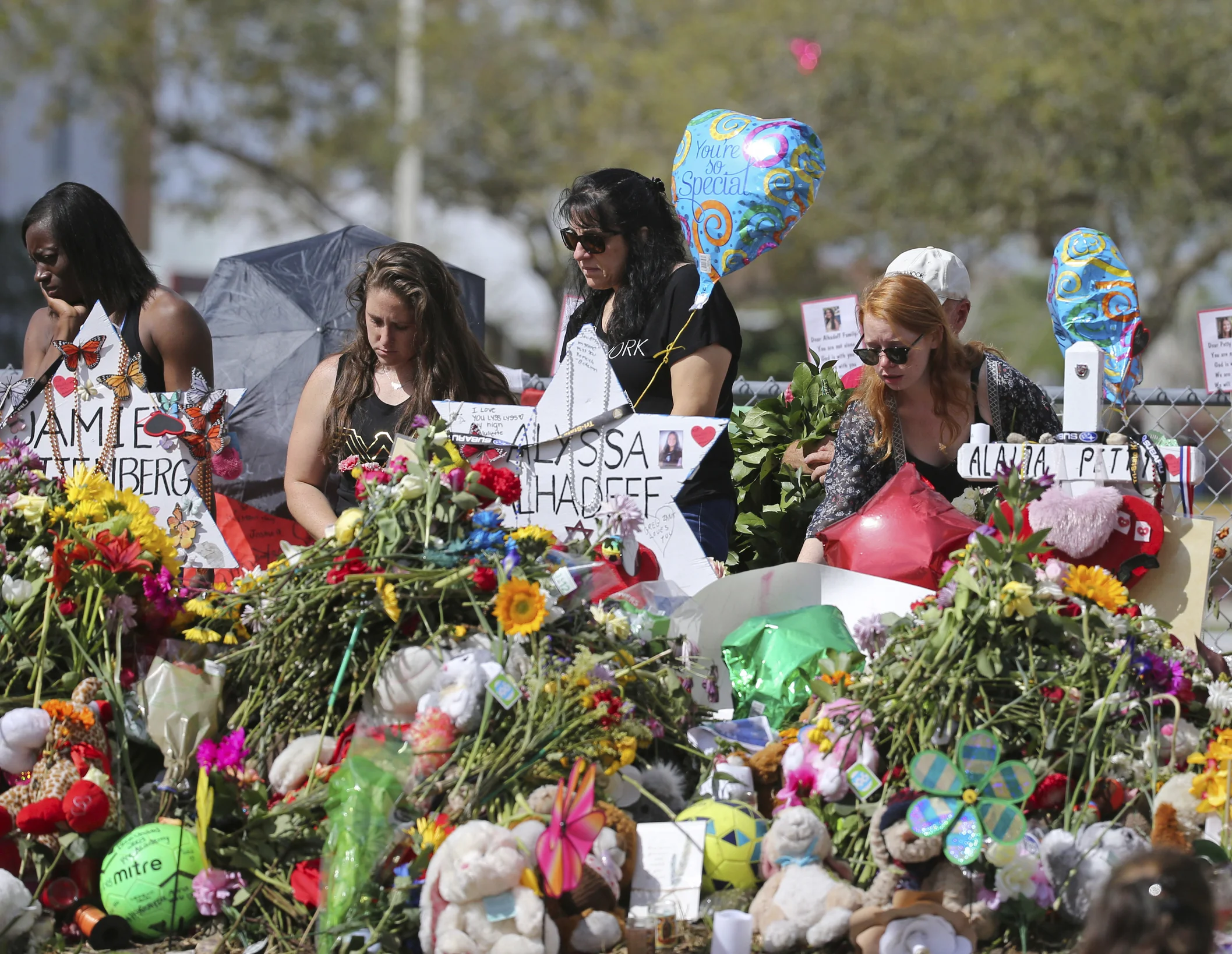 In this Feb. 25, 2018 file photo, mourners bring flowers as they pay tribute at a memorial for the victims of the shooting at Marjory Stoneman Douglas High School, in Parkland, Fla. The community of Parkland, Florida, is focusing on suicide prevention programs after two survivors of the Florida high school massacre there killed themselves this month. Parkland Mayor Christine Hunschofsky said Monday, March 25, 2019, that officials are publicizing the available counseling services after a second Marjory Stoneman Douglas High School student apparently killed himself over the weekend. (David Santiago/Miami Herald via AP, File)