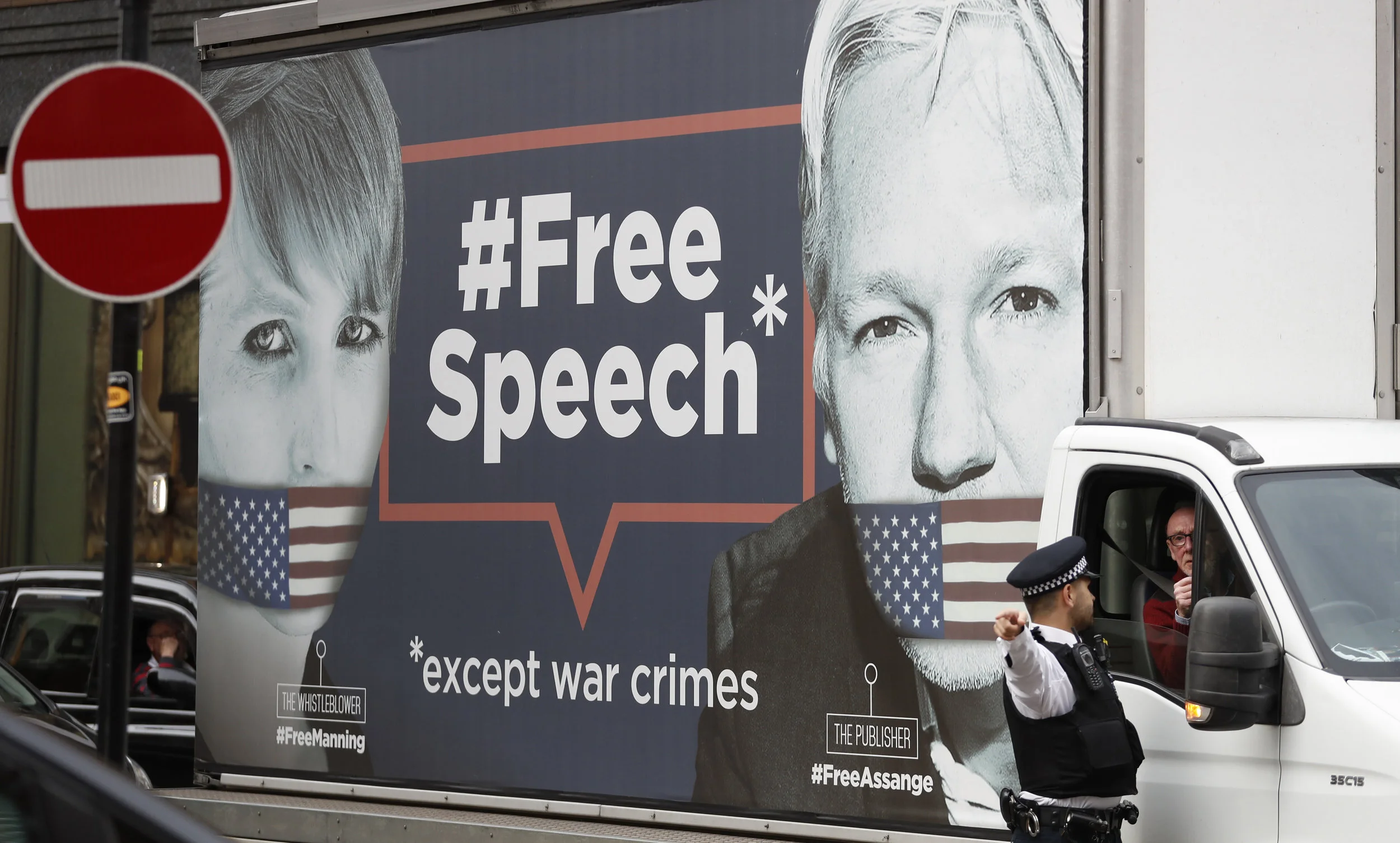 A policeman directs a van with a 'Free Speech' placard and the images of Wikileaks founder Julian Assange and whistleblower Chelsea Manning on its side, near the Ecuadorian Embassy, in London, Friday, April 5, 2019. Assange has been hold out since in the embassy since 2012. A senior Ecuadorian official said no decision has been made to expel Julian Assange from the country's London embassy despite tweets from Wikileaks that sources had told it he could be kicked out within "hours to days" on Friday. (AP Photo/Alastair Grant)