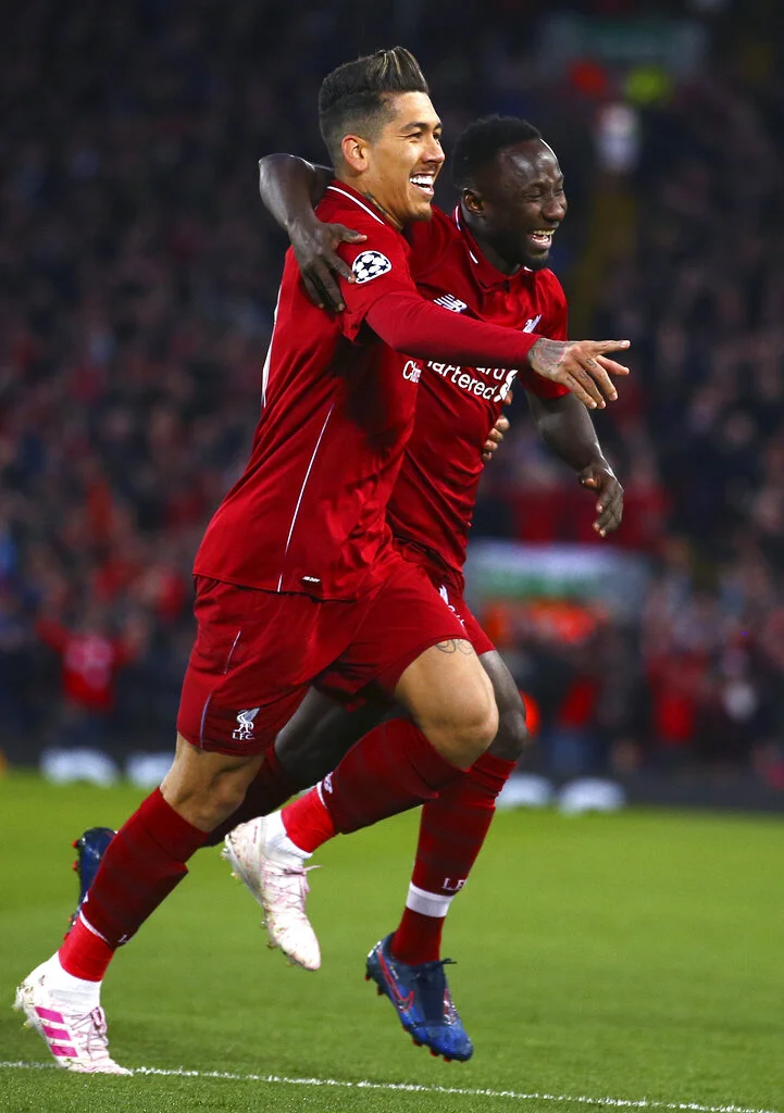 Liverpool's Naby Keita celebrates with Roberto Firmino, left, after scoring the opening goal during the Champions League quarterfinal, first leg, soccer match between Liverpool and FC Porto at Anfield Stadium, Liverpool, England, Tuesday April 9, 2019. (AP Photo/Dave Thompson)