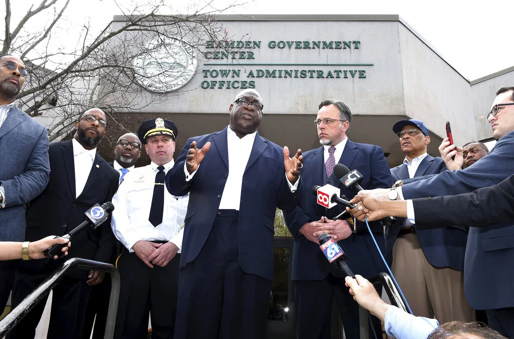 Rev. Boise Kimber, center, flanked by Hamden Acting Police Chief John Cappiello, left, and Hamden Mayor Curt Leng, right, addresses the media outside of the Hamden Government Center after a meeting between the town officials and local clergy concerning the recent shooting by a Hamden police officer, Friday, April 19, 2019 in Hamden, Conn.. (Arnold Gold/Hearst Connecticut Media via AP)