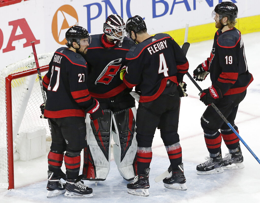 Carolina Hurricanes goalie Curtis McElhinney is congratulated by Justin Faulk (27), Haydn Fleury (4) and Dougie Hamilton (19) following the Hurricanes' 5-2 win over the New York Islanders in Game 3 of an NHL hockey second-round playoff series in Raleigh, N.C., Wednesday, May 1, 2019. (AP Photo/Gerry Broome)