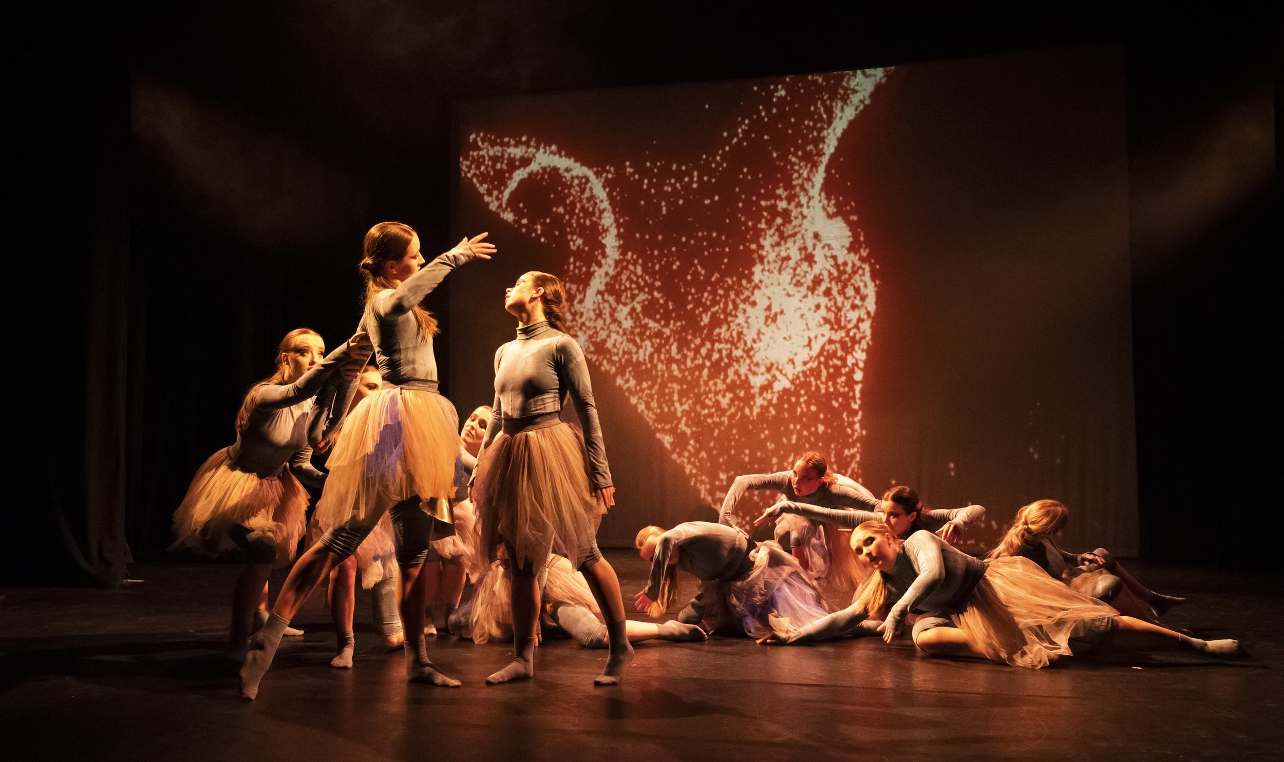 dancers in front of particle projection in amber light 