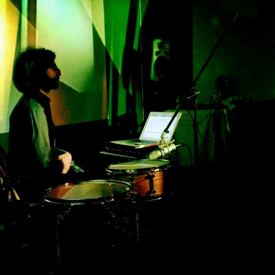 Thursday July 12th 8PM $10 Drums and Drones is the solo project of Brian Chase ( Yeah Yeah Yeahs / John Zorn) and is performed in conjunction with the stunning visuals of video artist Ursula Scherrer . The project uses drums and percussion as a medium for ‘going inside the sound:’ that of constructing expansive soundscapes, like aural snapshots of tone, to uncover the richness of sonic depth hidden within the resonance of these instruments. Similarly, the visual component investigates and reconstructs elements of found forms, whether in filmed objects or simply light itself. In the live video projections, an architectural abstraction continues to emerge and re-evolve, and layers stack to reveal shifting fields of depth and perception. Drums and Drones credits initial inspiration to La Monte Young and Marian Zazeela’s legendary Dream House installation in TriBeCa, NYC. Evan Miller is a percussionist and improviser based in Dayton, OH. He works with percussion, found objects, cassette tapes, and field recordings to create music drawing equally from drone and free improvisation. Evan is also a member of Neutrals, an experimental percussion duo, with Andrew Seivert. http://evanmillerperc.com Sarah Hughes is an alto saxophonist, composer, and music educator from Pasadena, Maryland. She is a free improviser who enjoys creating within and on top of many genre frameworks including jazz, swing, blues, folk pop, and rock. Sarah has toured Sweden as part of their first annual Women in Jazz Festival, and has shared the bill, opening for great free improvisers such as Joe Morris, Nicole Mitchell, Fay Victor, William Parker, Hamid Drake, and Ken Vandermark. She also serves as adjunct faculty at Towson University and McDaniel College. http://www.sarahmariehughes.com