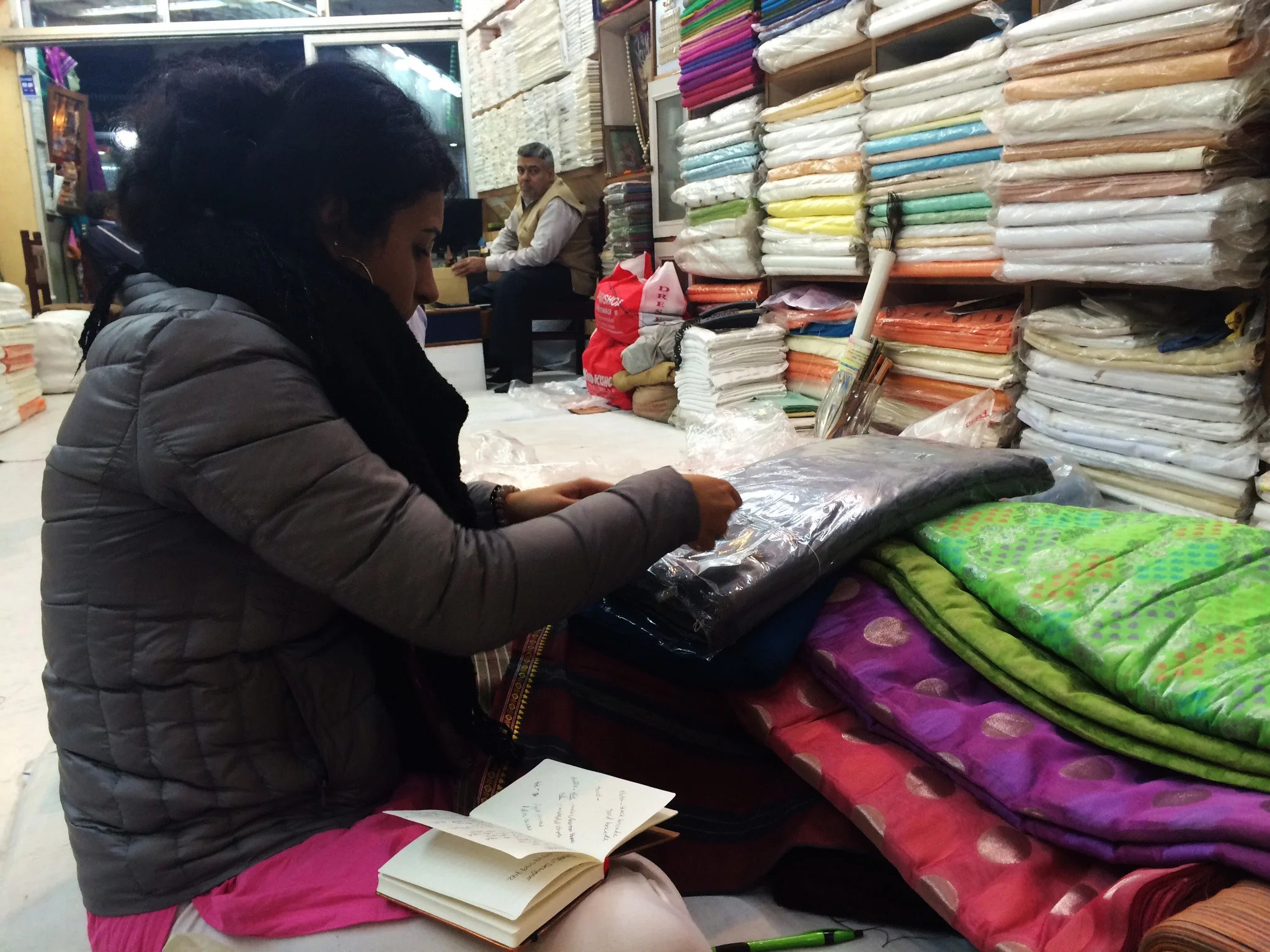  Textile shopping is a process that is very service oriented where the salesperson assists in picking out the best pieces that the shop has to offer. Here we see Reshma quality checking her favorite picks after the salesman unfurled them for her. 