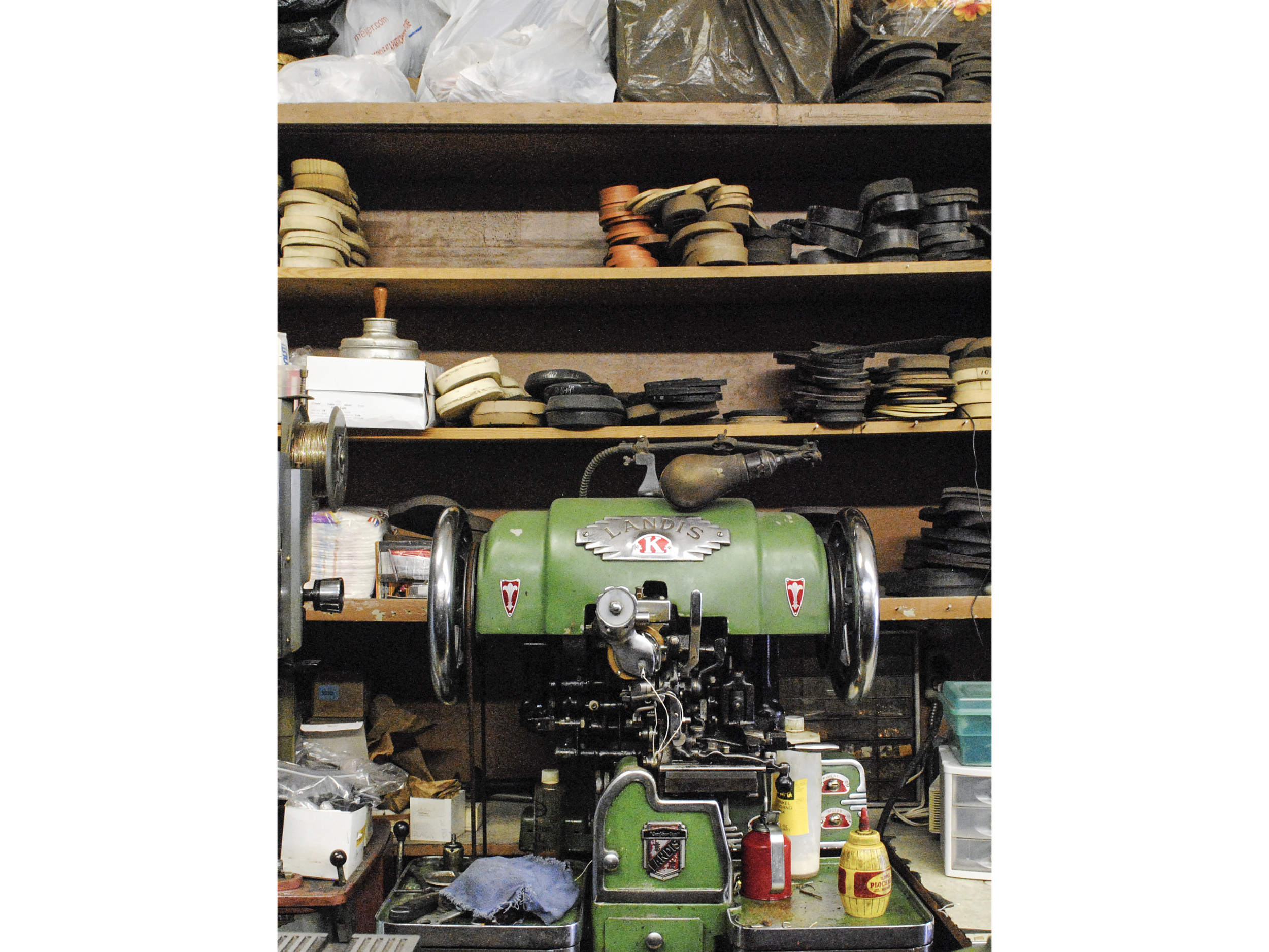 Shoe sole sewing machine. Stacks of soles on shelves above.