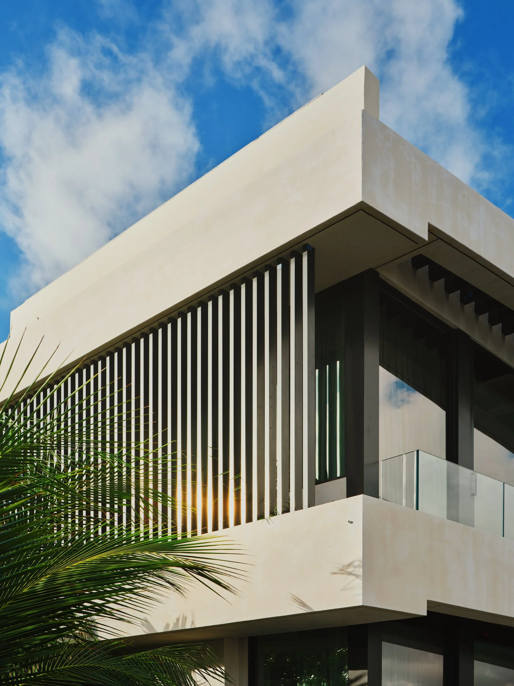 Architectural photograph of a modern Miami residence on the Venetian Islands featuring sculptural concrete volumes and vertical louvers catching the afternoon sun. Captured by Miami and Los Angeles-based architectural and travel photographer Christia