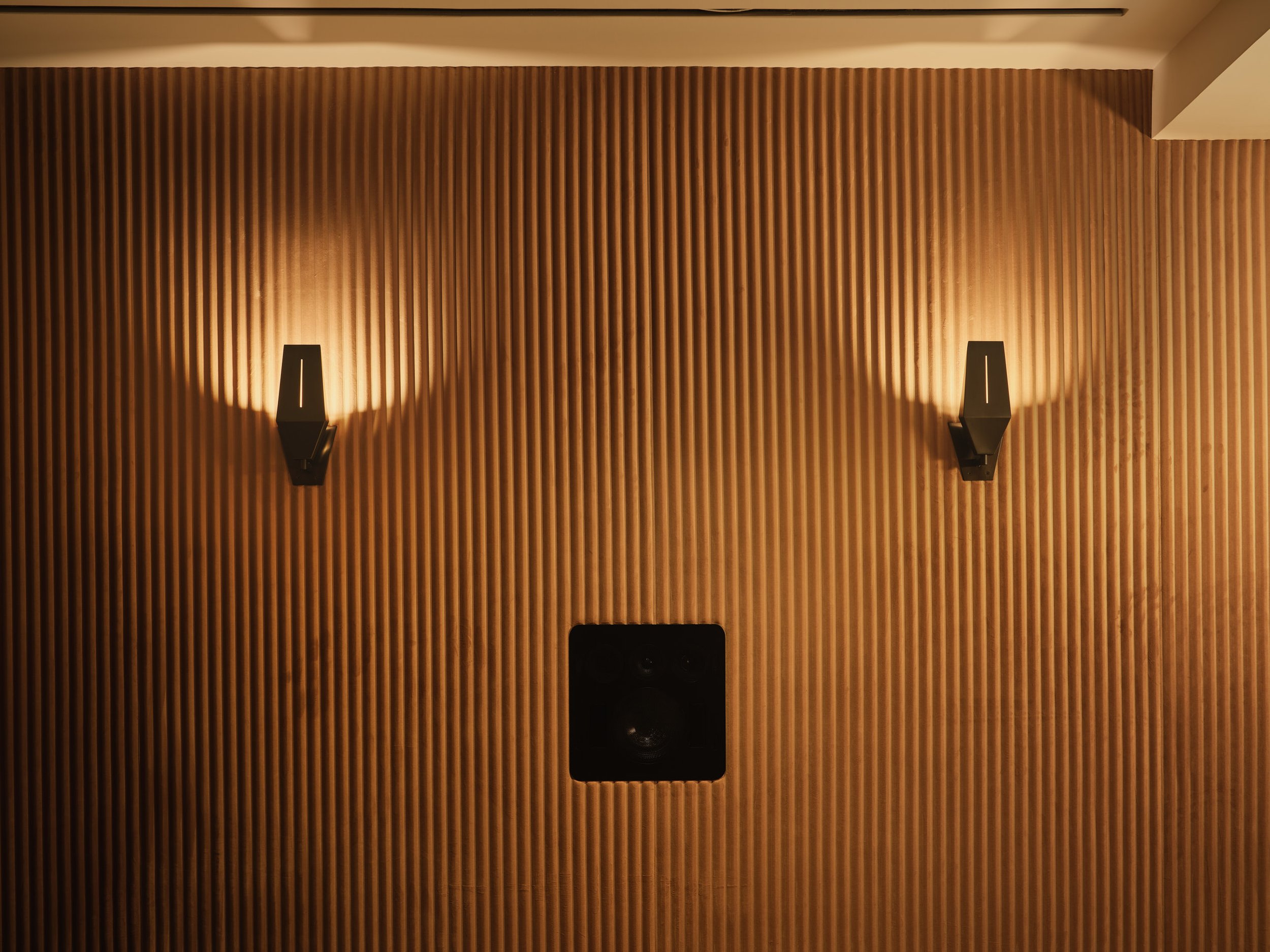 Architectural photograph of symmetrical wall sconces illuminating vertical wood acoustic panels in a private luxury home theater in Miami. Captured by Miami and Los Angeles-based architectural and travel photographer Christian Santiago.