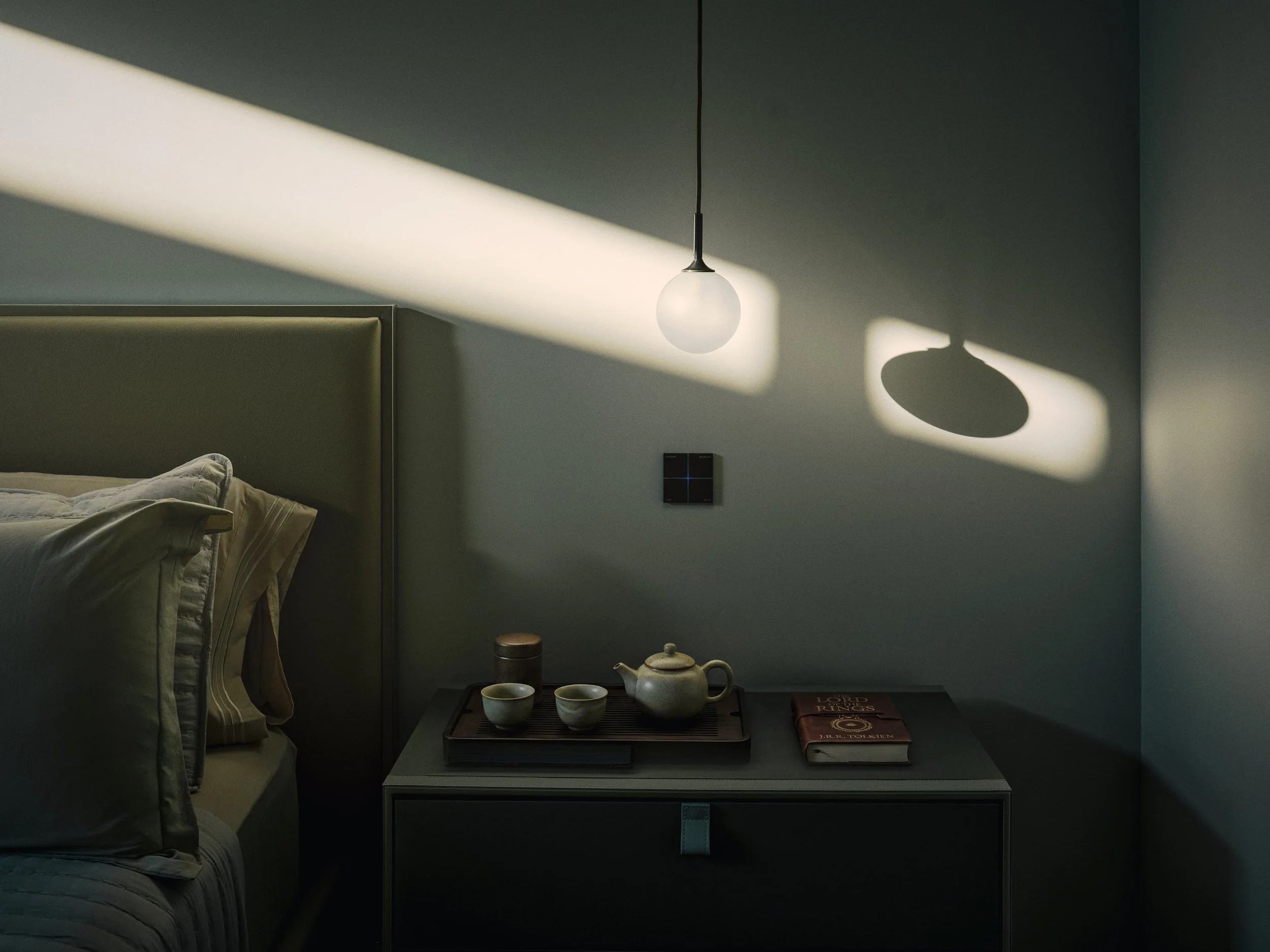 Architectural photograph of natural light casting dramatic shadows across a minimalist bedroom nightstand with pendant lighting inside a modern Miami residence. Captured by Miami and Los Angeles-based architectural and travel photographer Christian S