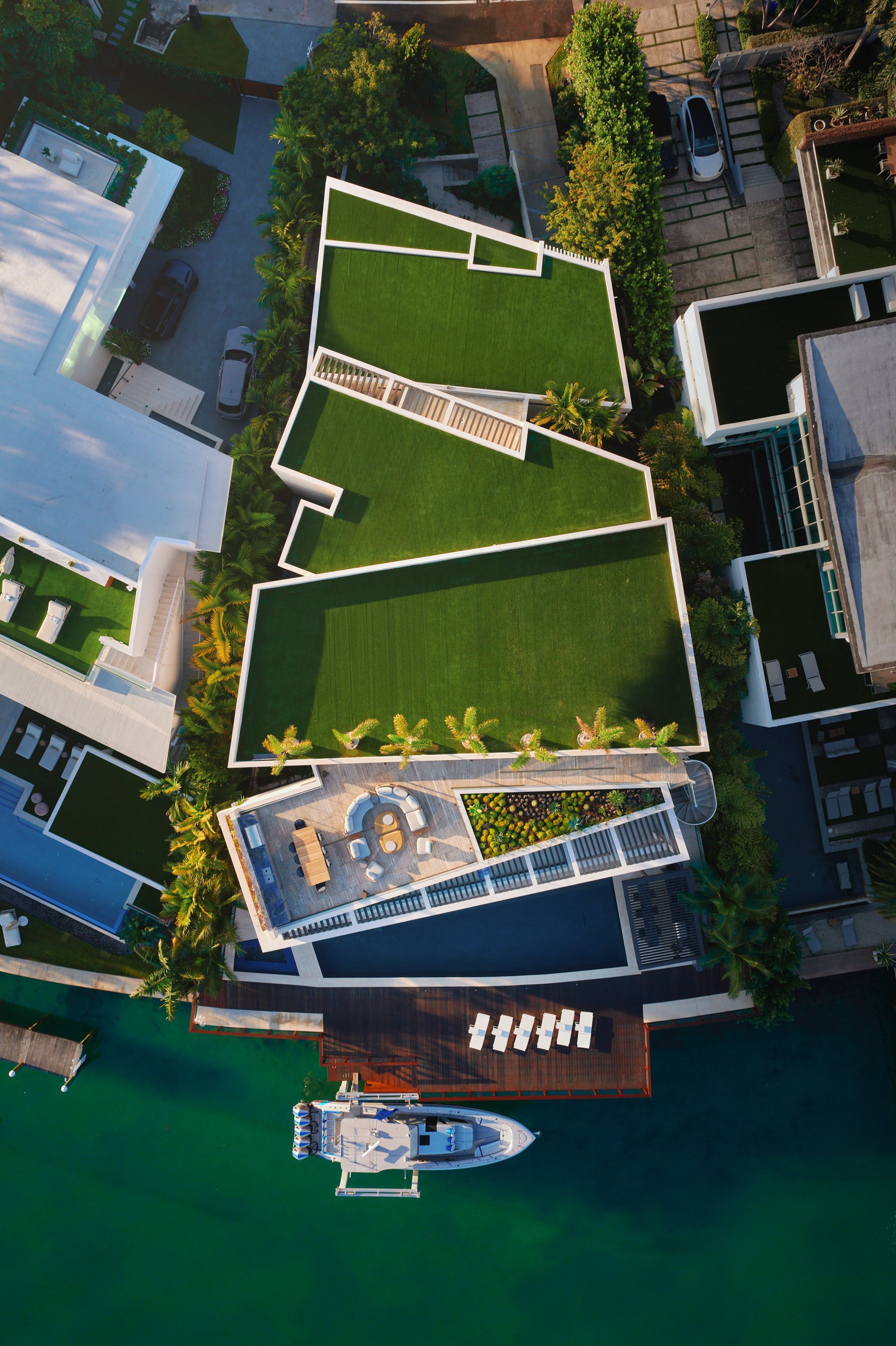 Architectural drone photograph of a waterfront luxury residence in Miami, Florida highlighting the rooftop lawn, trapezoidal floorplan and private dock. Captured by Miami & Los Angeles-based architectural photographer Christian Santiago