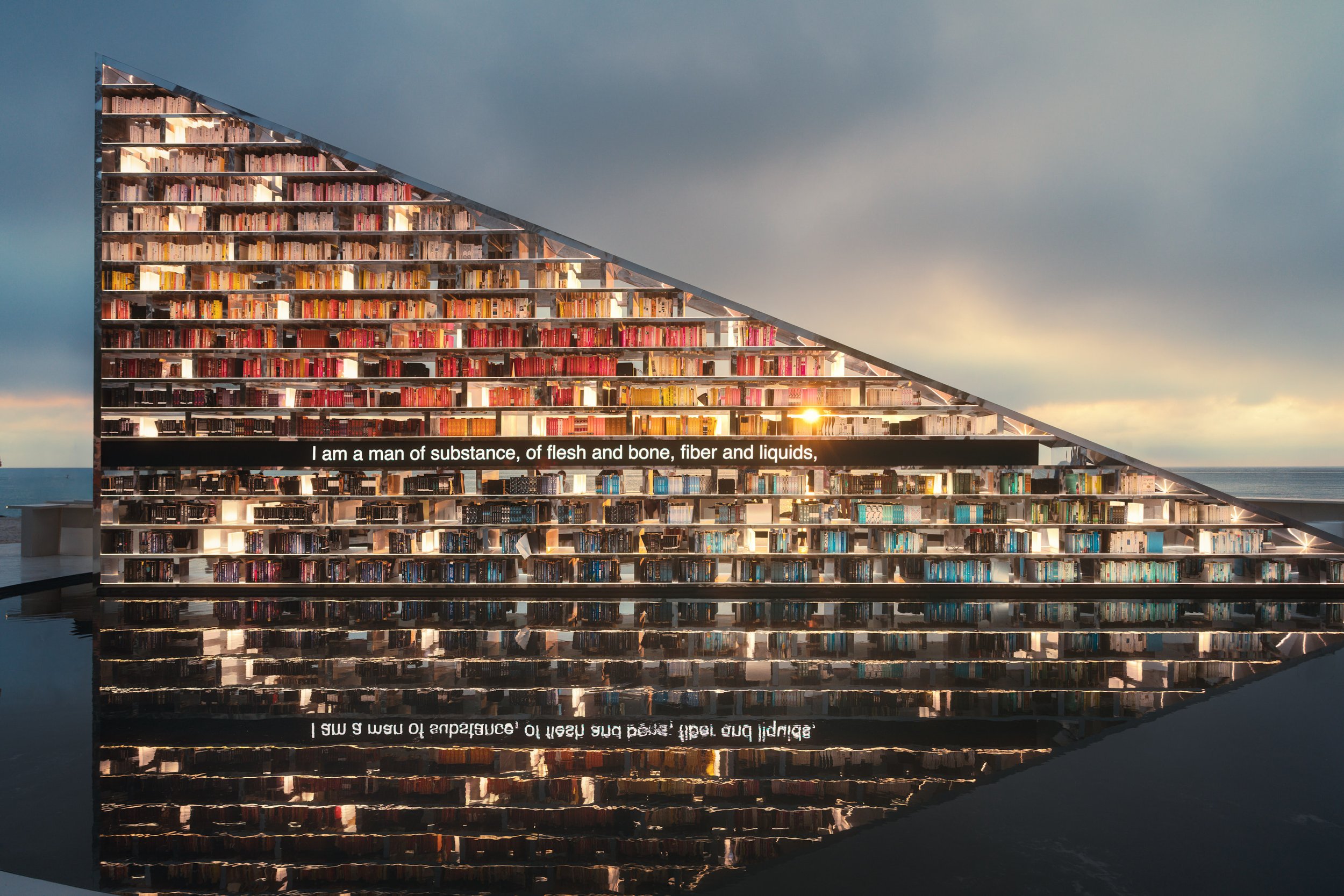 Architectural photograph of Es Devlin’s Library of Us public art installation at Faena Miami Beach during Art Basel Miami Beach, featuring the illuminated triangular bookshelf structure filled with books and reflected in water at sunset. The image em
