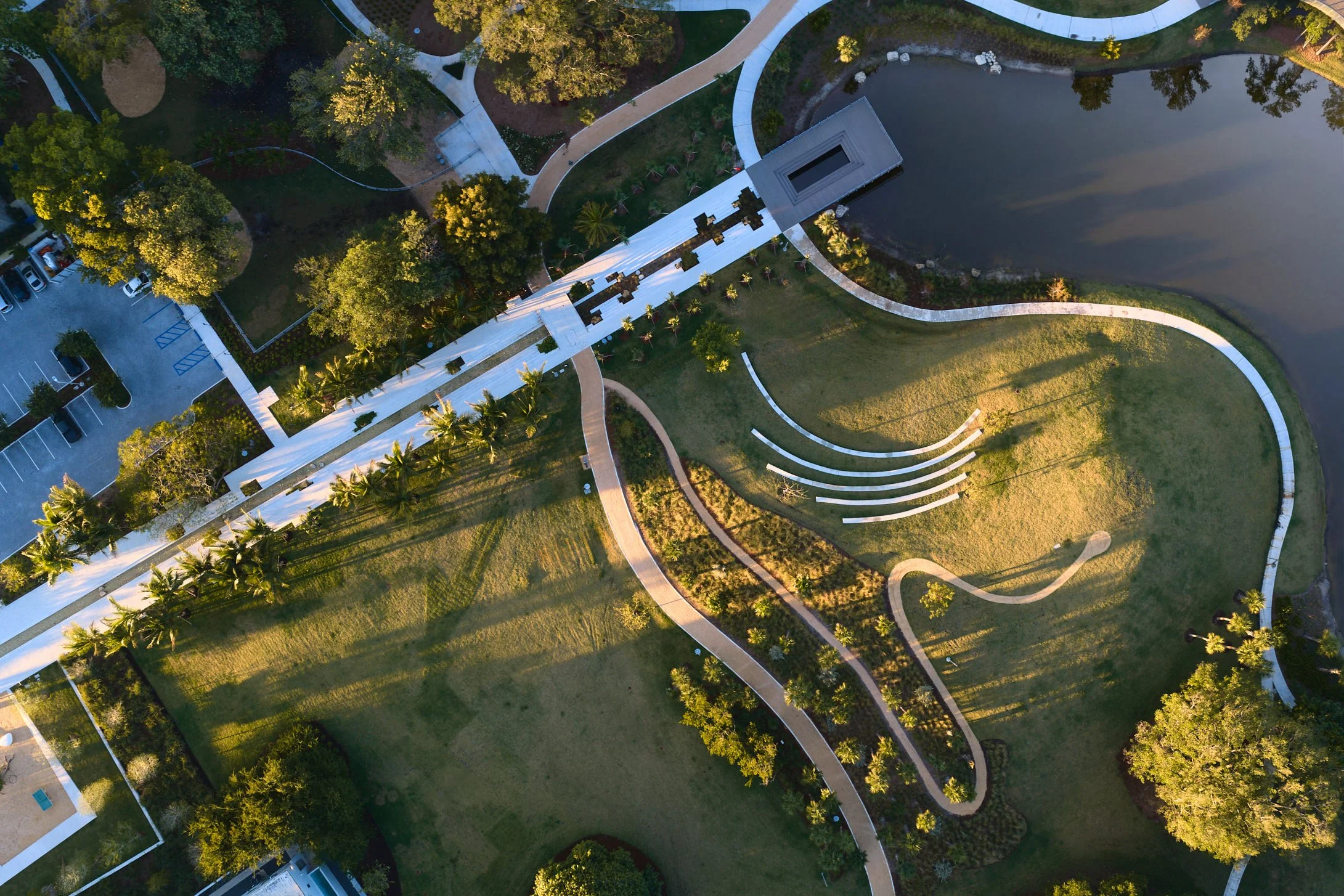 Architectural aerial photograph of Bayshore Park in Miami Beach revealing the park’s landscape architecture design, including curving walking paths, amphitheater seating, pedestrian bridge, and stormwater lake integrated into the urban park masterpla